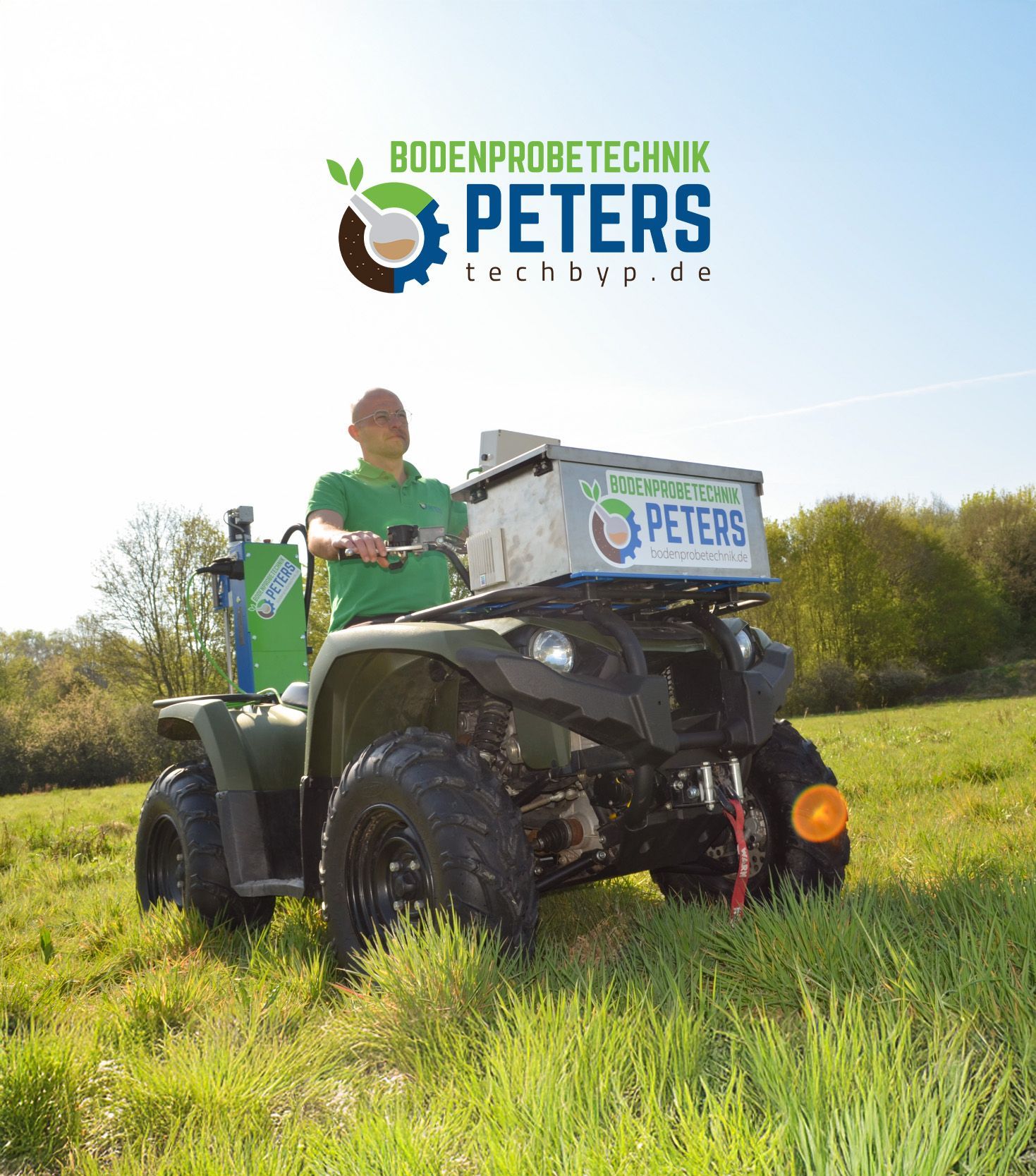 Ein grün-gelber Traktor besprüht ein Grasfeld.