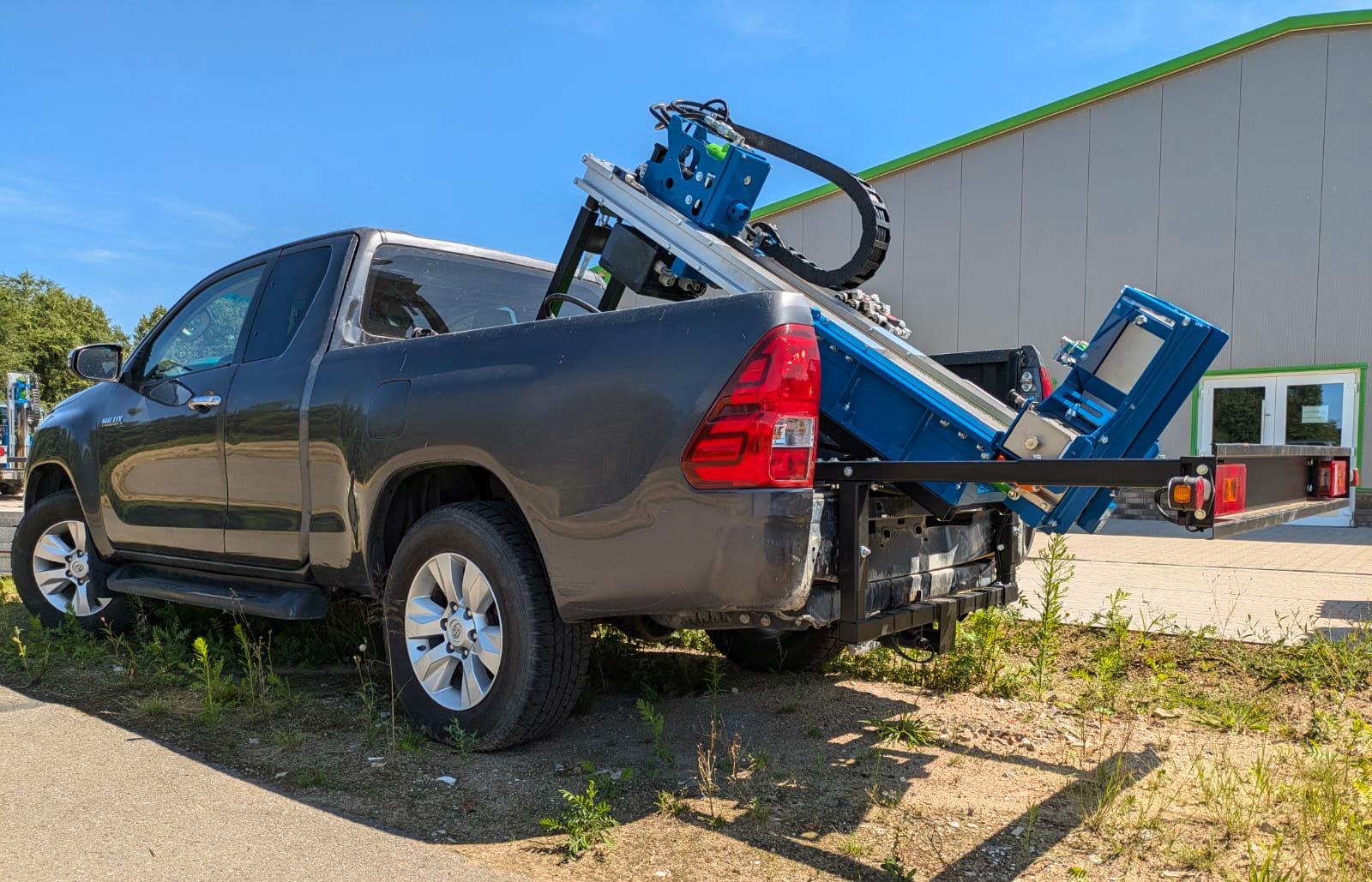 Vor einem Gebäude parkt ein Lastwagen mit einer Maschine auf der Ladefläche.