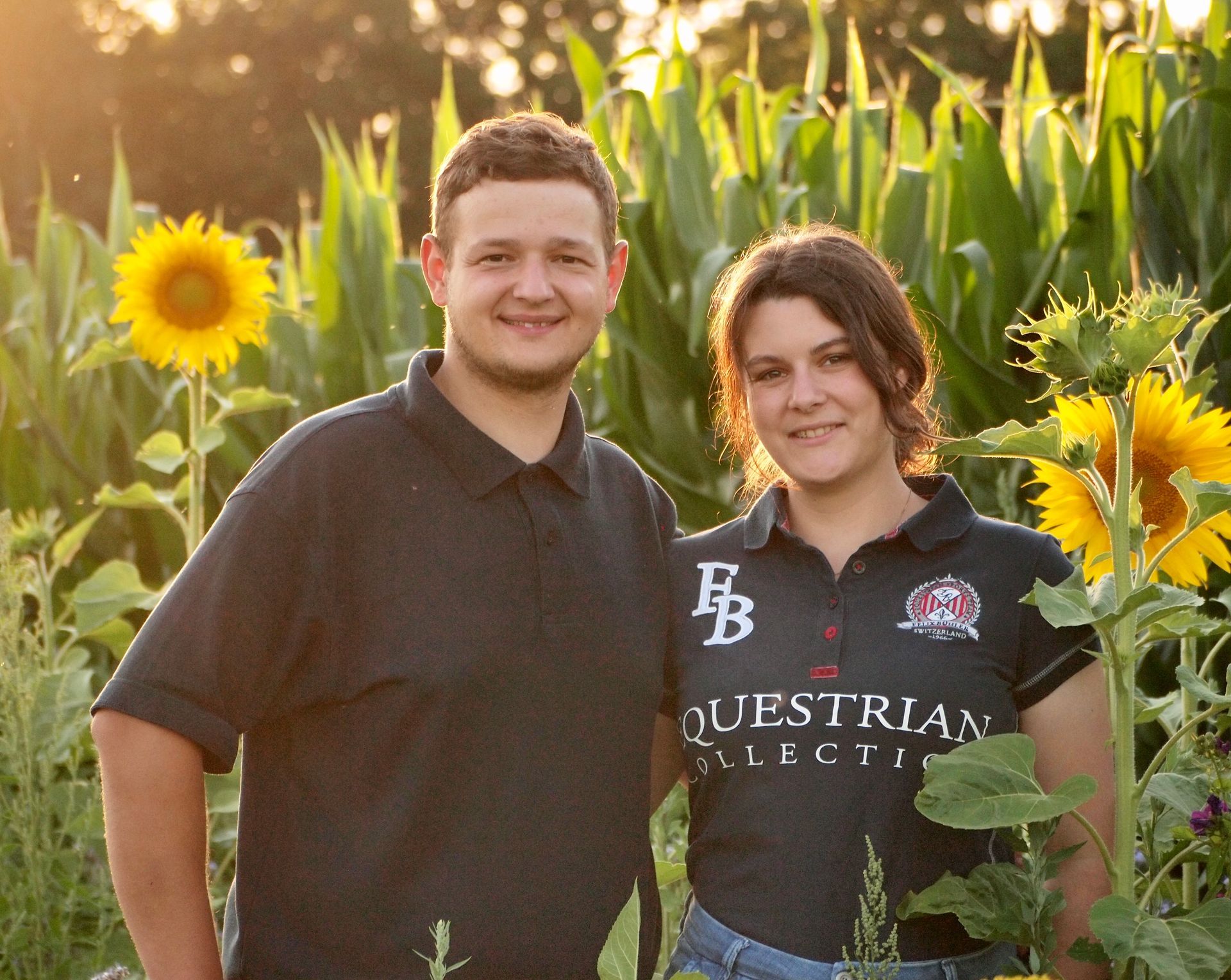 Ein Paar steht in einem Sonnenblumen- und Maisfeld. Sonnenlicht erhellt sie.