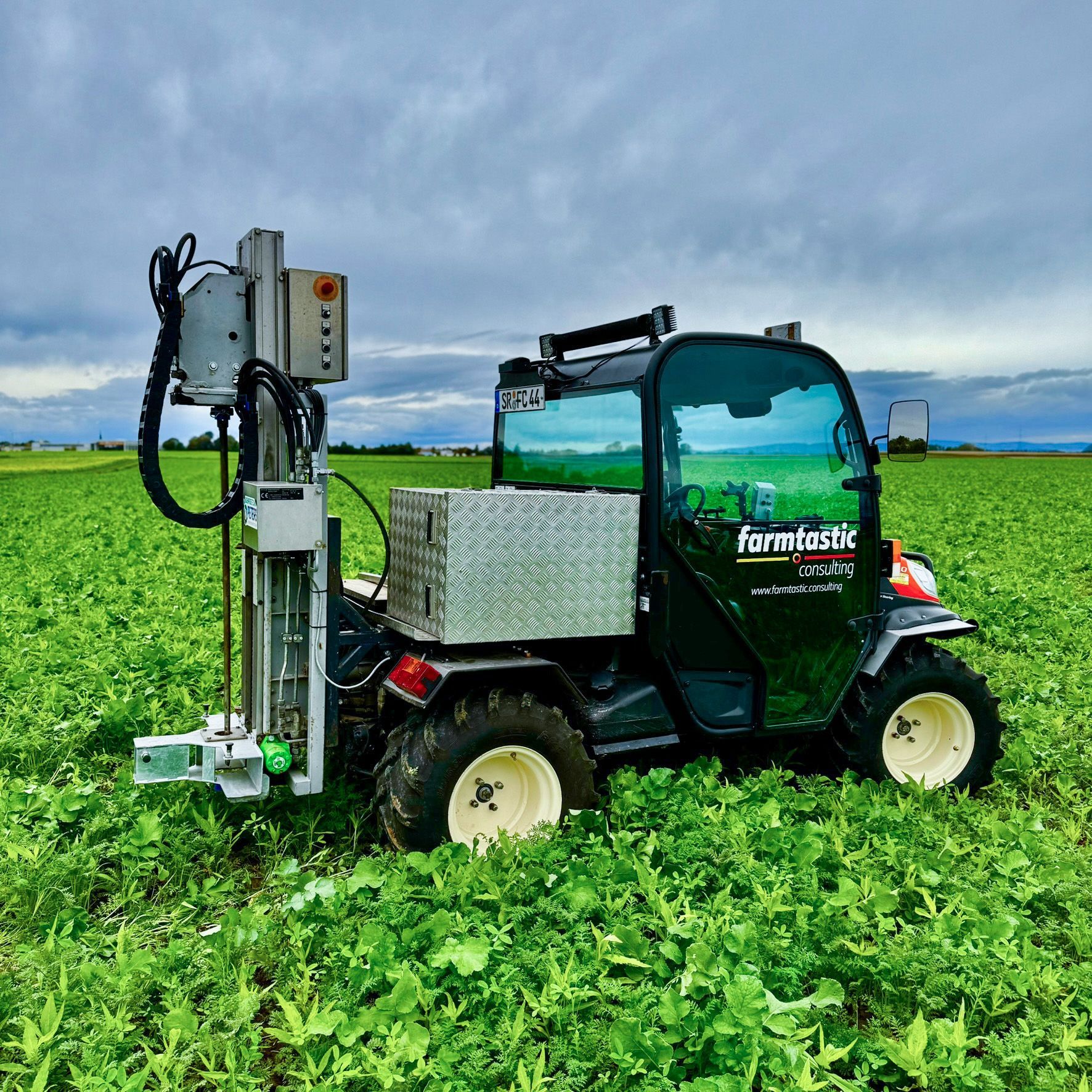 Ein grün-gelber Traktor besprüht ein Grasfeld.