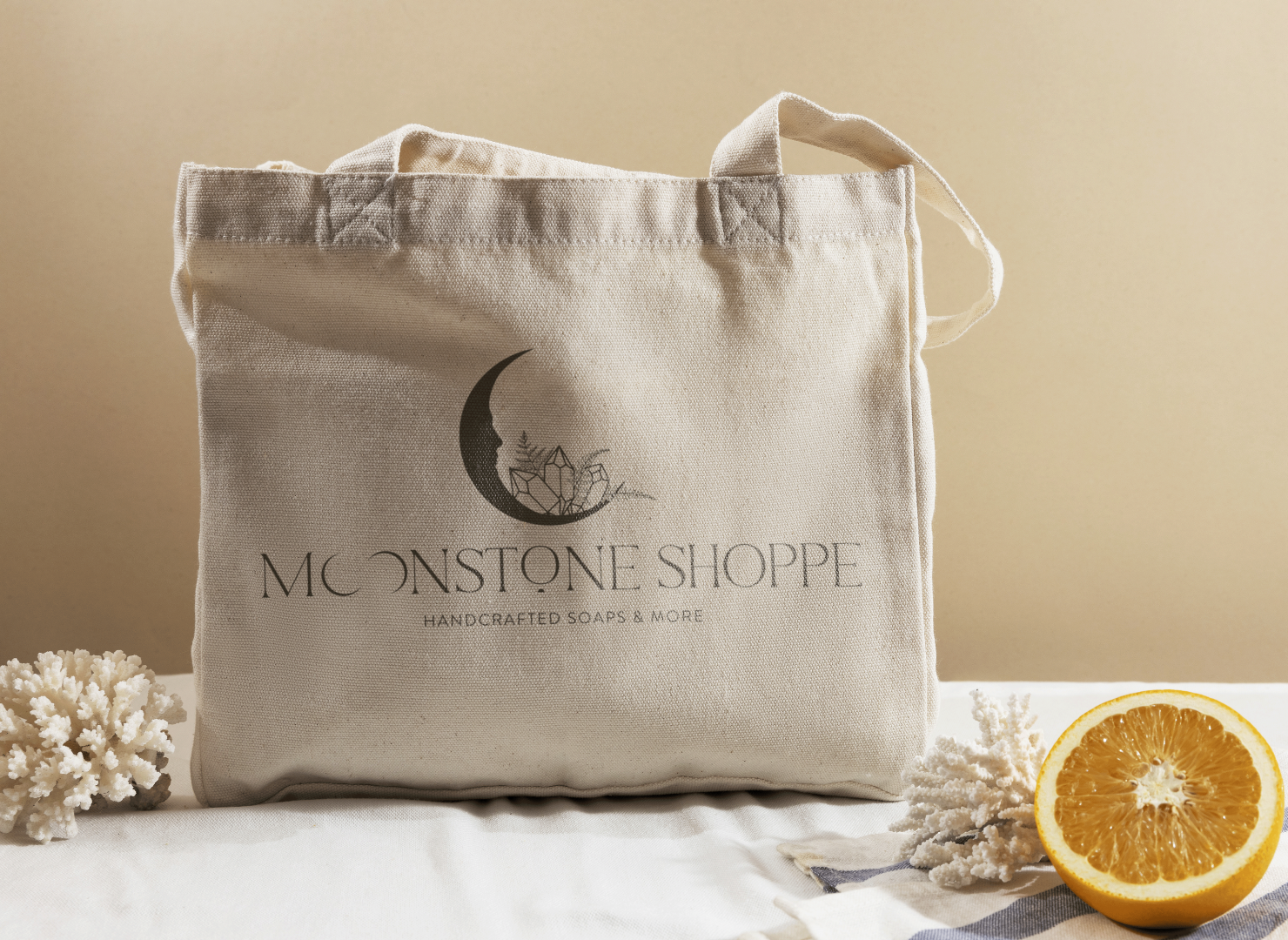 A tote bag is sitting on a table next to an orange.