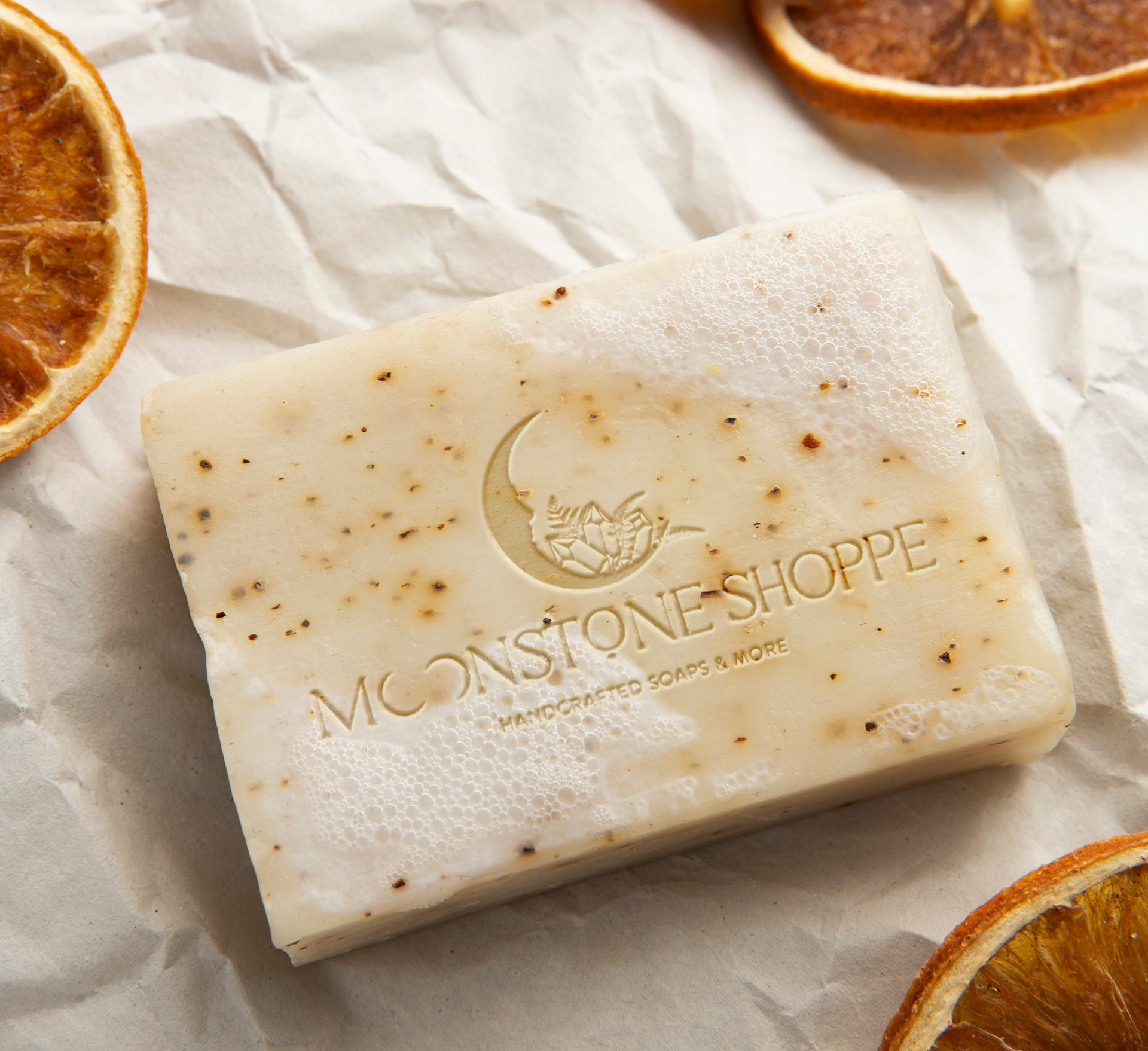 A bar of monstone shoppe soap is surrounded by oranges