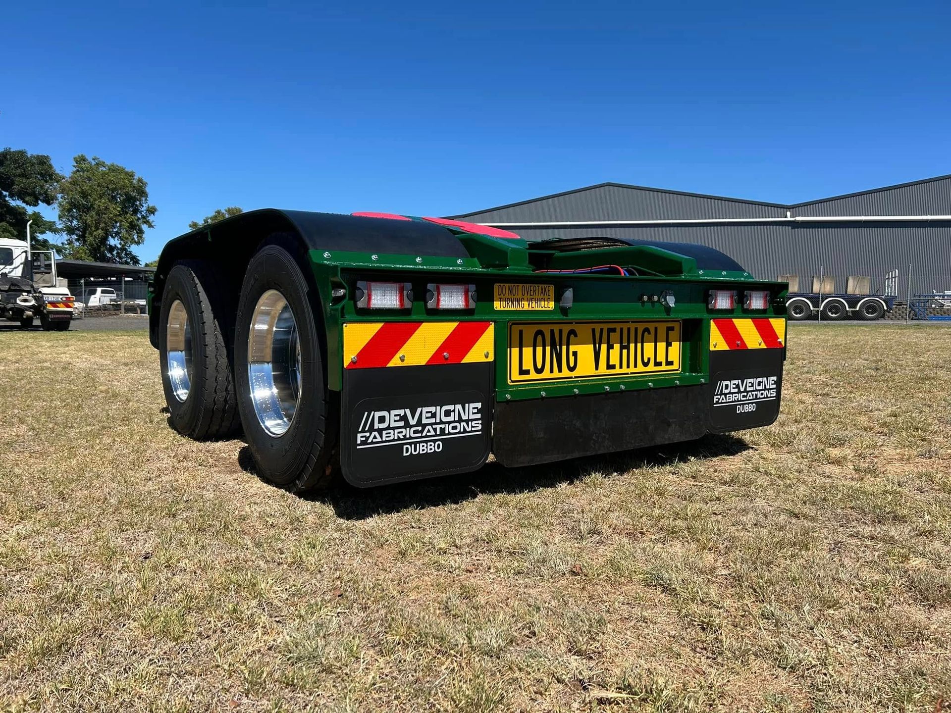 A Flatbed Trailer is Parked in a Grassy Field — Deveigne Fabrications In Brocklehurst, NSW