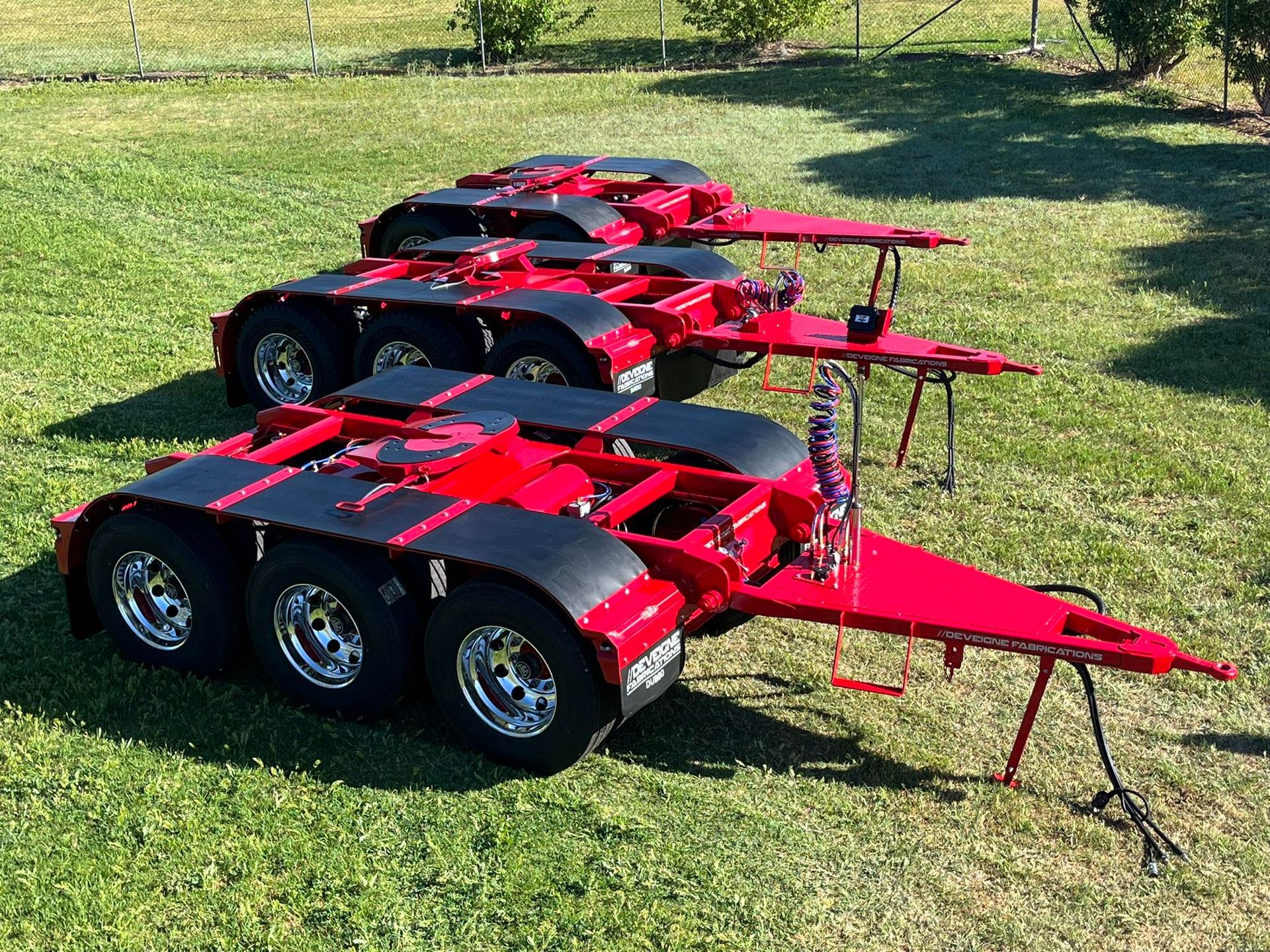 A row of dollies parked on the grass — Deveigne Fabrications In Brocklehurst, NSW