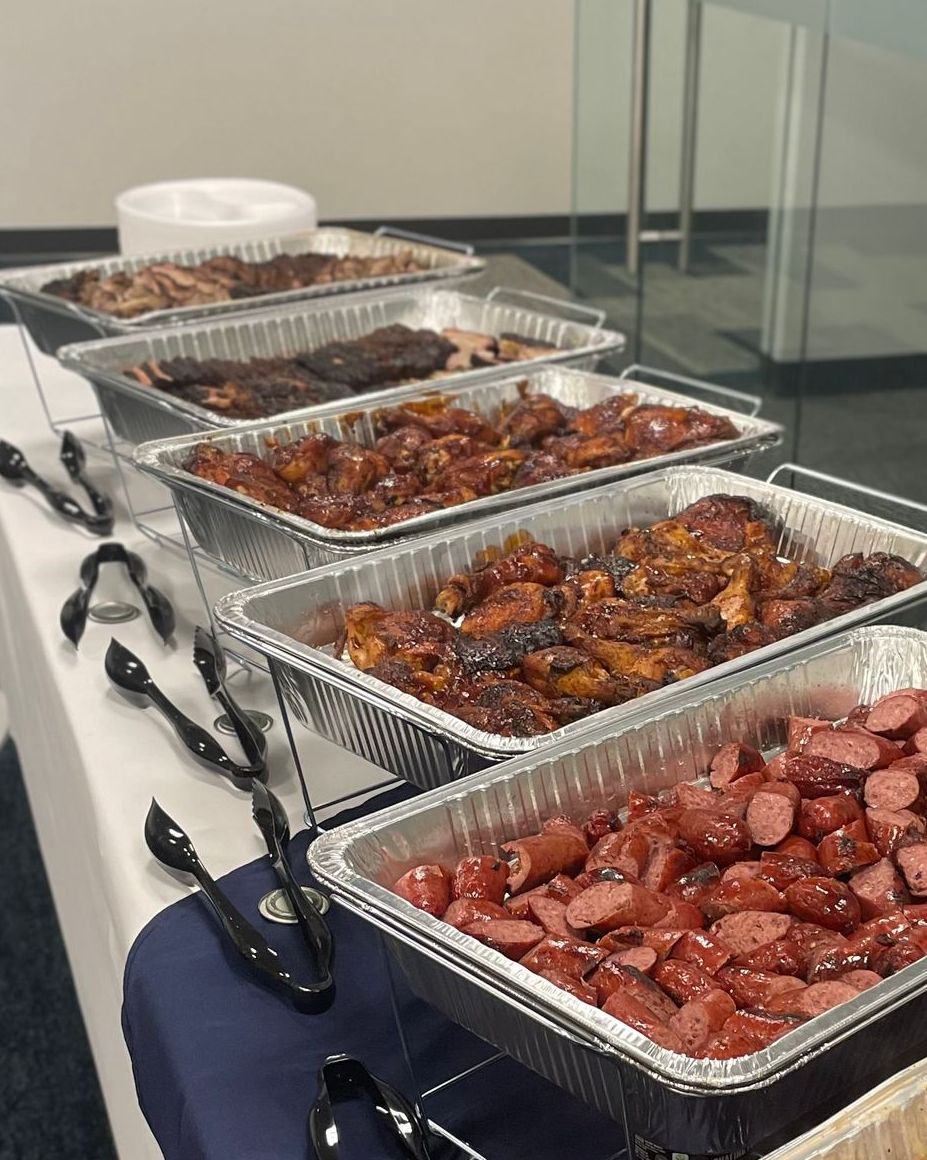 A buffet table with a variety of food in foil trays.