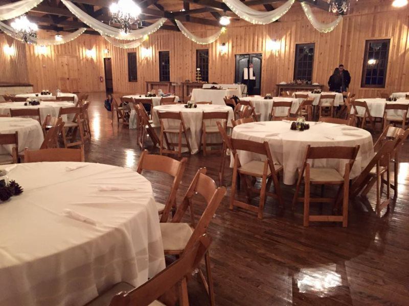 A large room with tables and chairs set up for a wedding reception