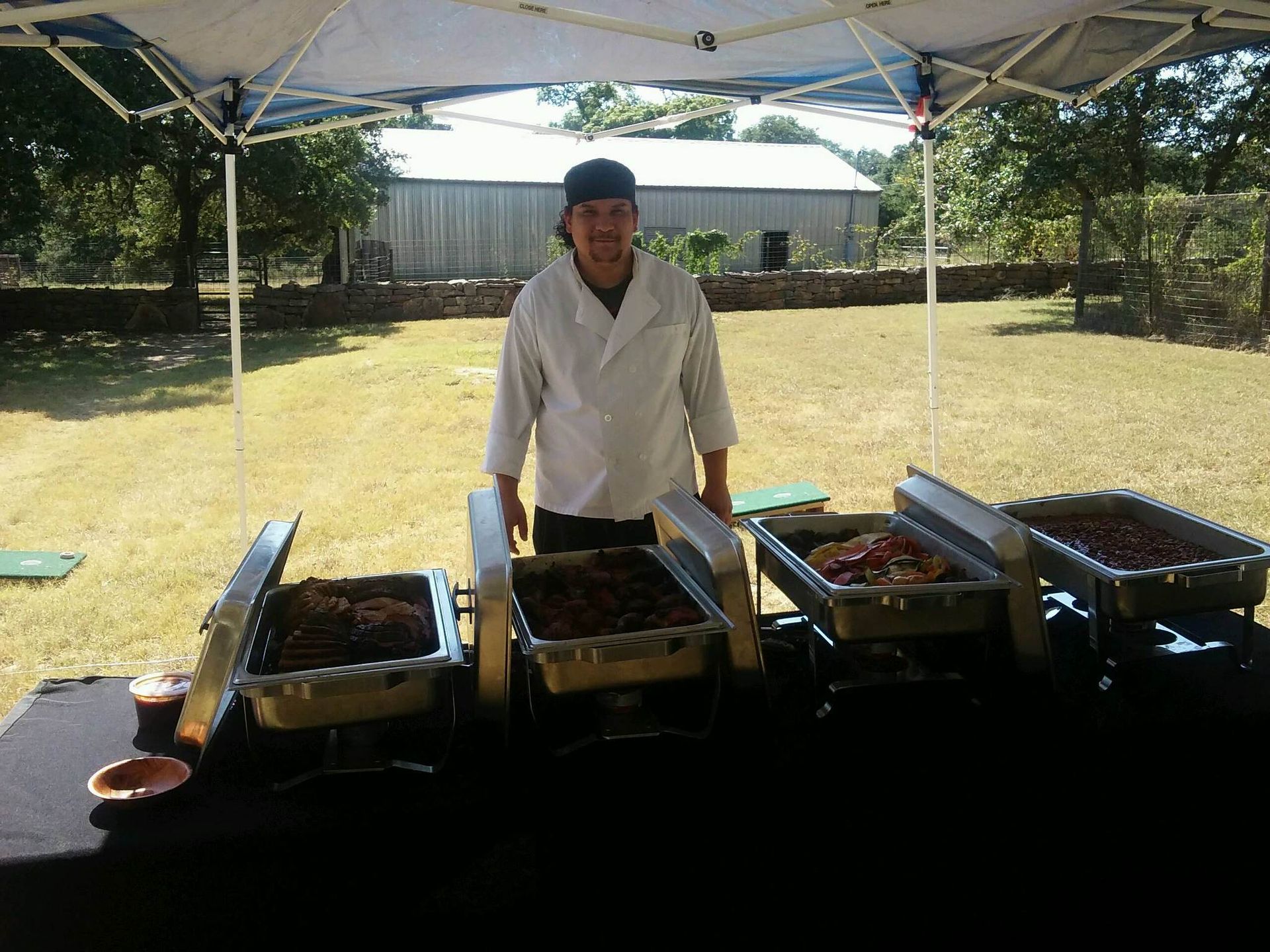 A man in a white coat stands in front of a buffet line