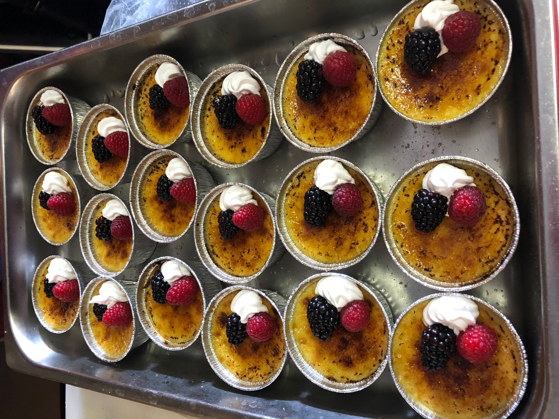 A tray of desserts with whipped cream and berries on top