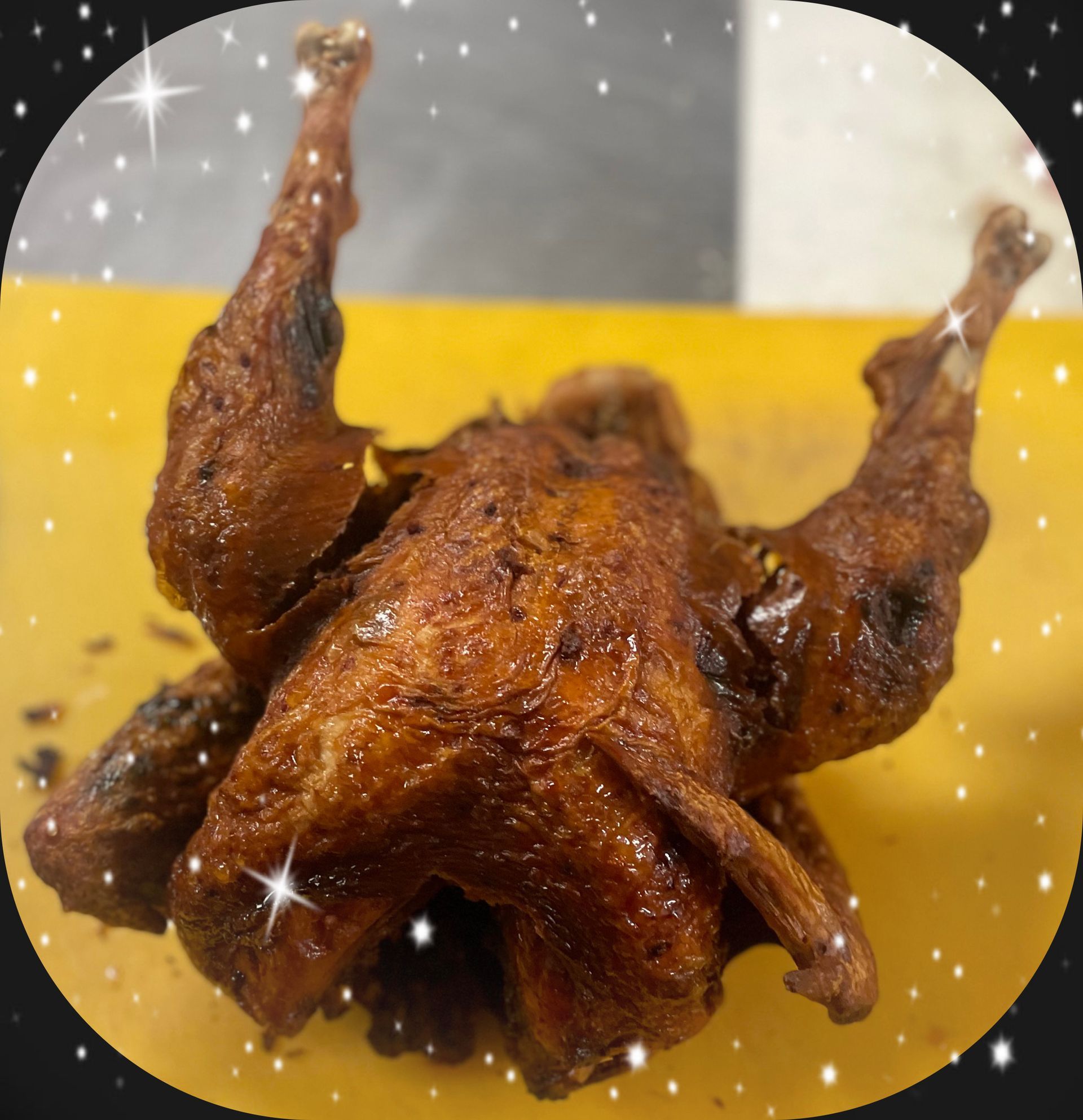 A roasted chicken is laying on its back on a yellow cutting board