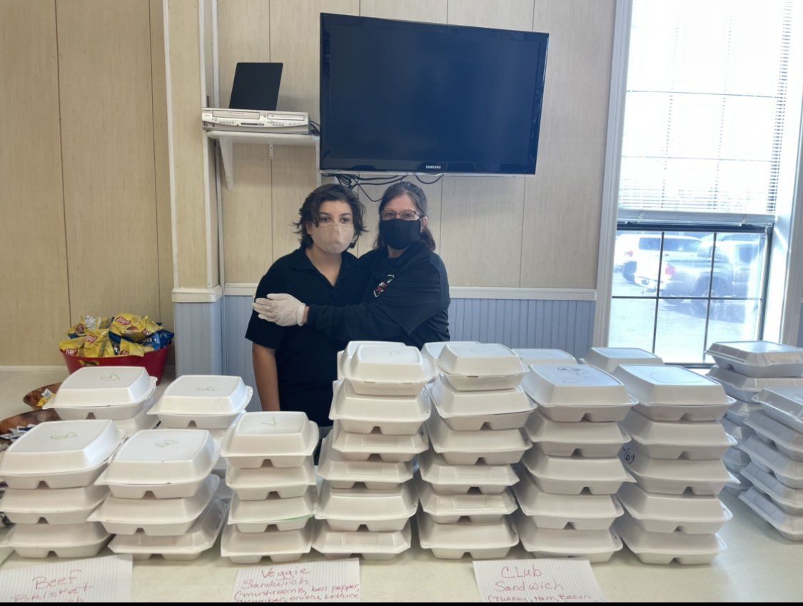 two people standing in front of a table full of styrofoam containers