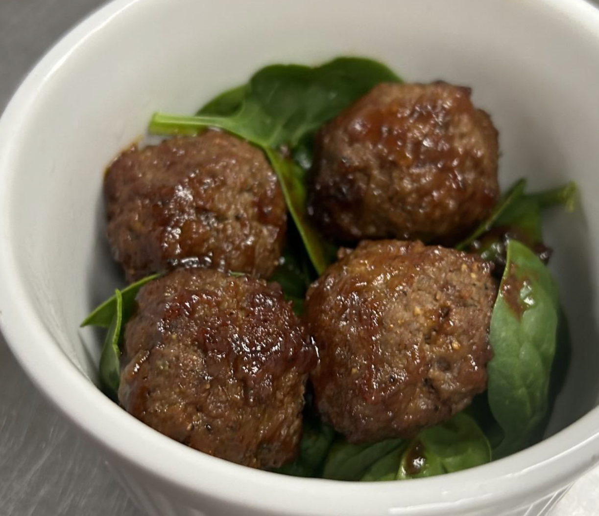 A white bowl filled with meatballs and greens