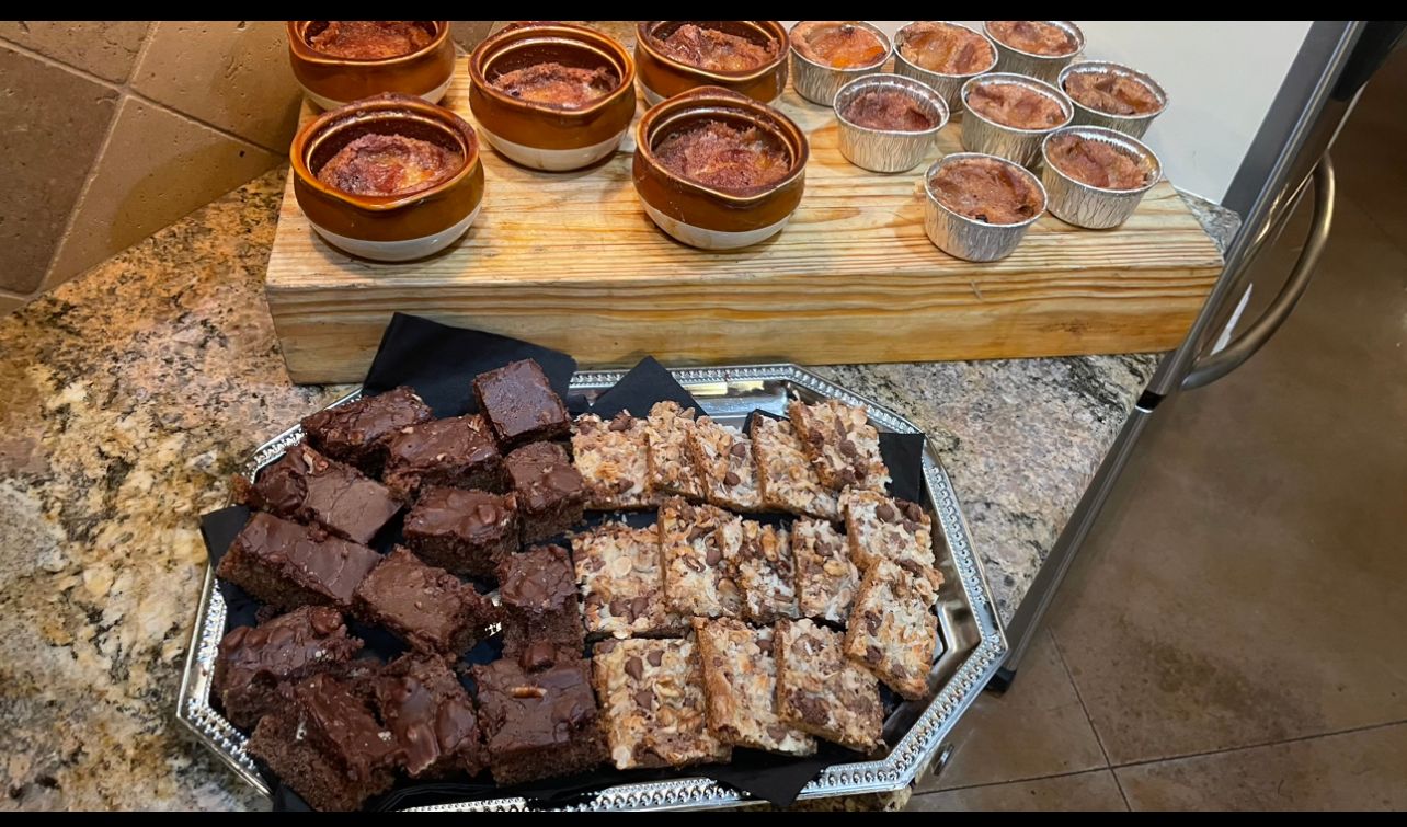A tray of brownies and a tray of desserts on a counter.