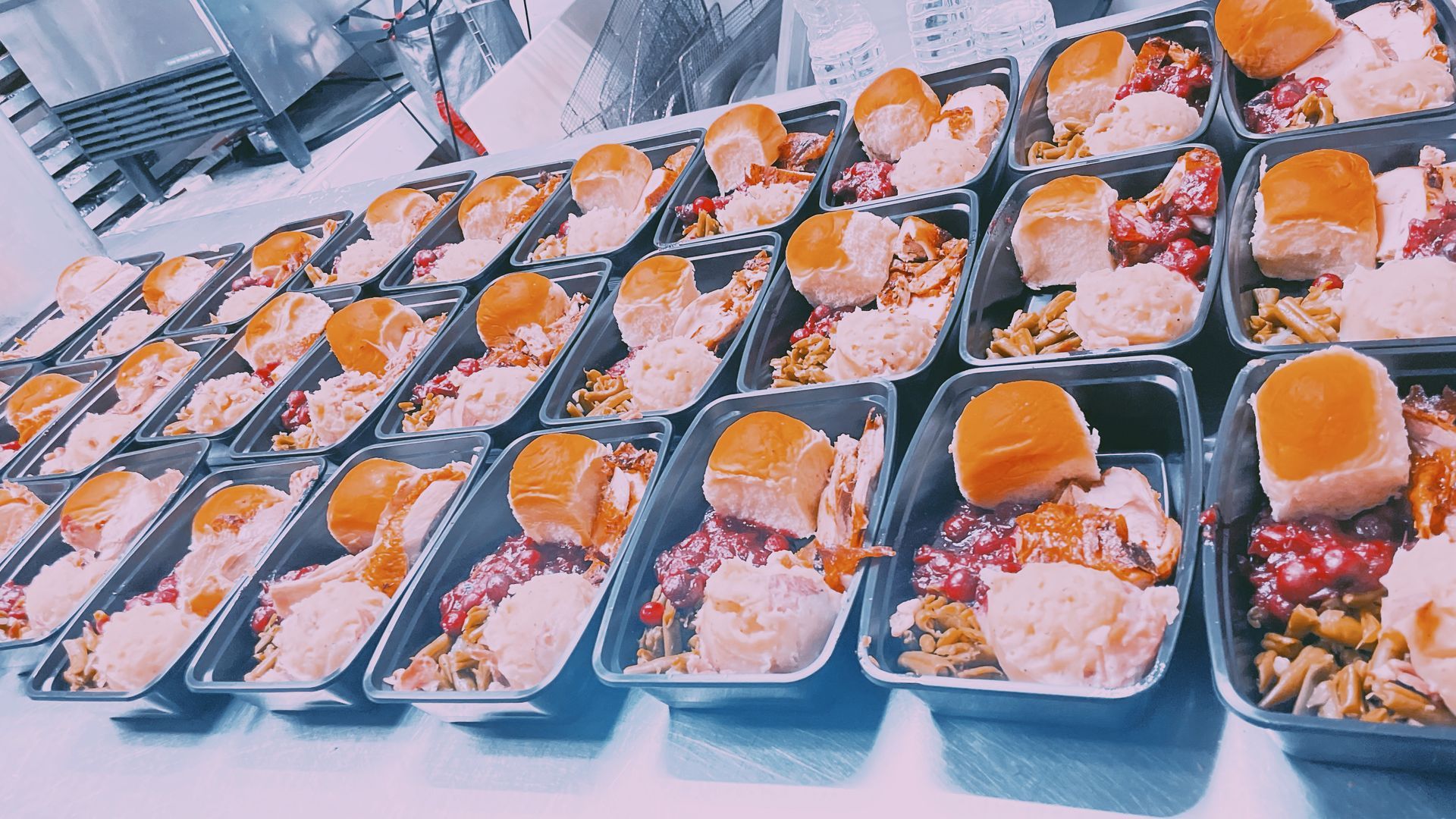 A bunch of containers of food are lined up on a table.