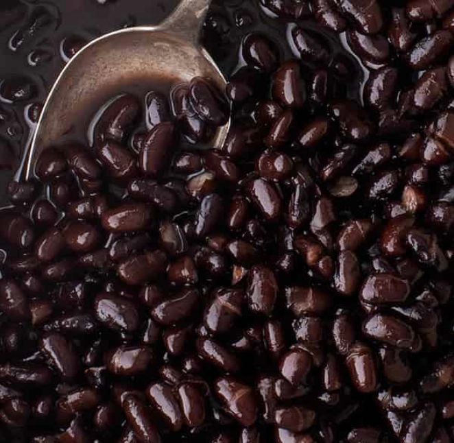 A bowl of black beans with a spoon in it