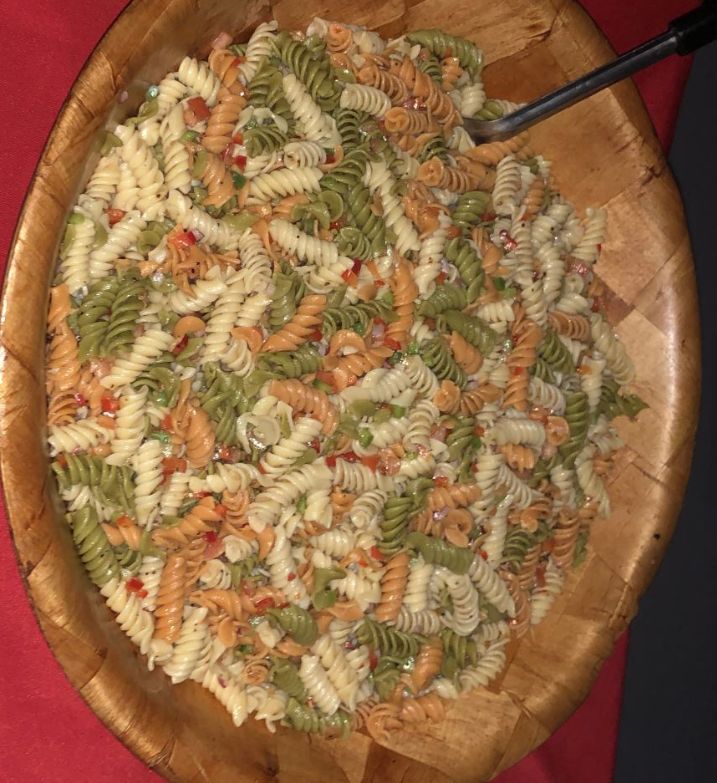 A bowl of pasta salad with a spoon in it