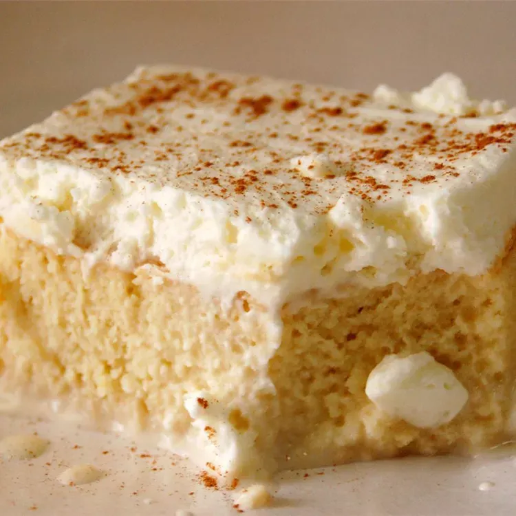 A piece of cake with whipped cream on top on a white plate.