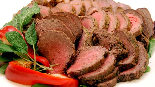 A plate of meat and vegetables on a white background.