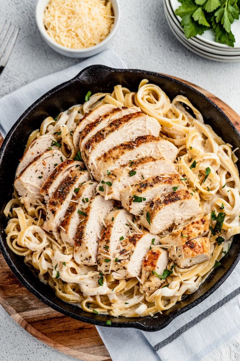 A skillet filled with pasta and chicken on a table.