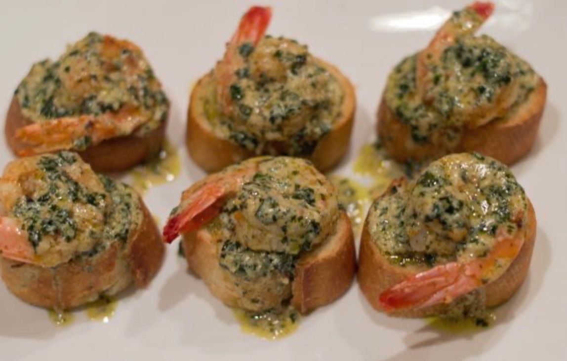 A white plate topped with shrimp and spinach on bread