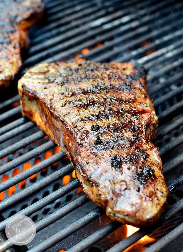 A close up of a steak cooking on a grill.