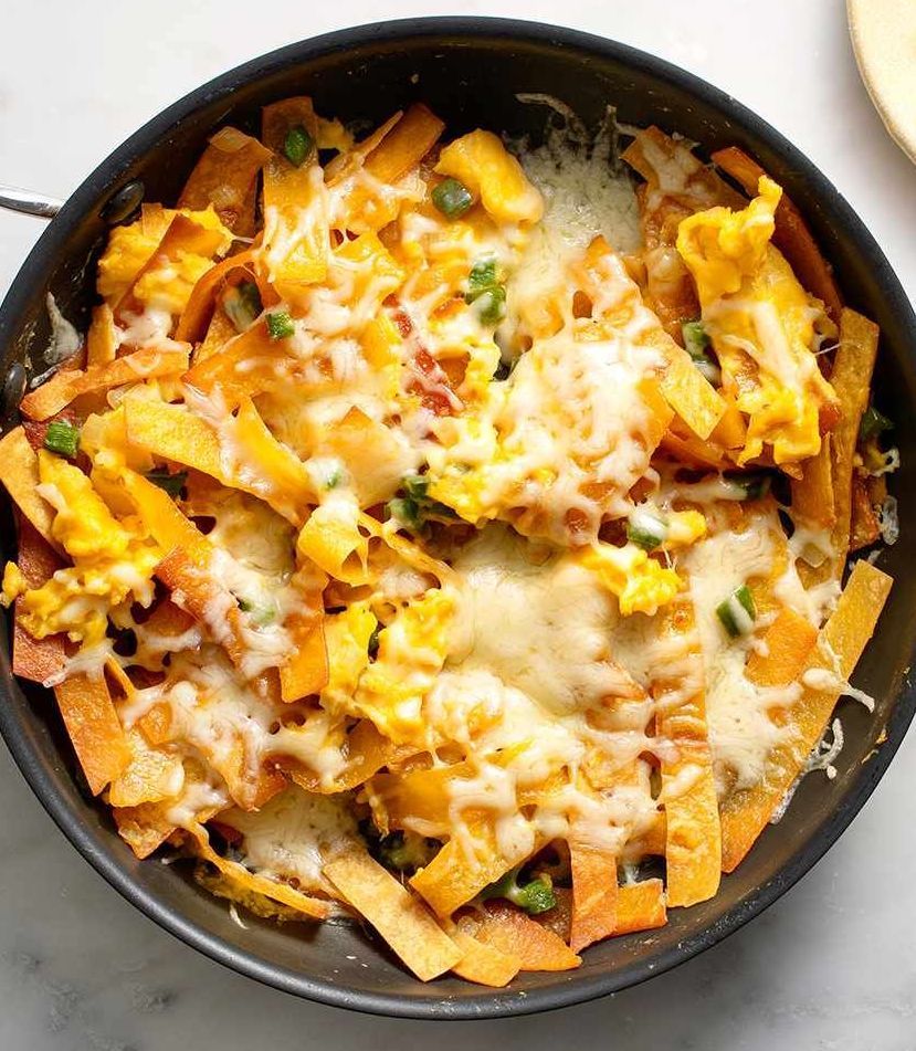 A pan filled with tortilla chips and cheese on a table.