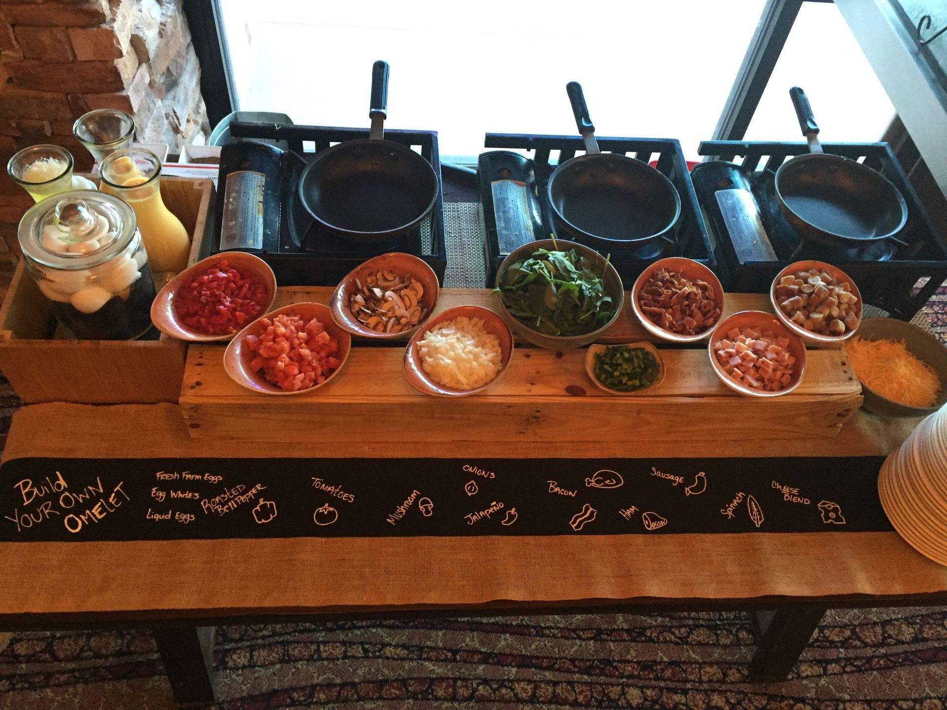 A wooden table topped with bowls of food and pans.
