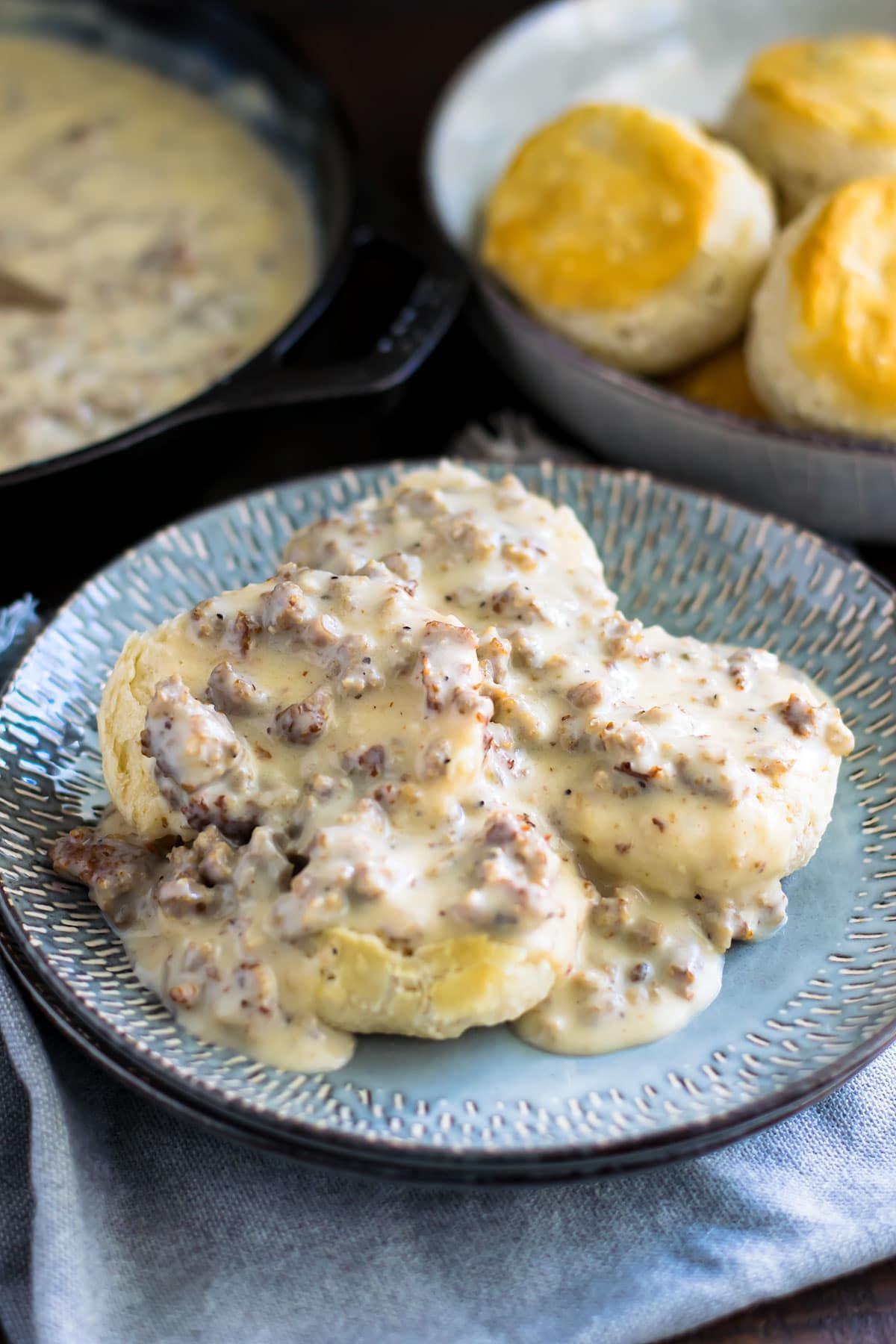 A plate of sausage gravy and biscuits on a table.