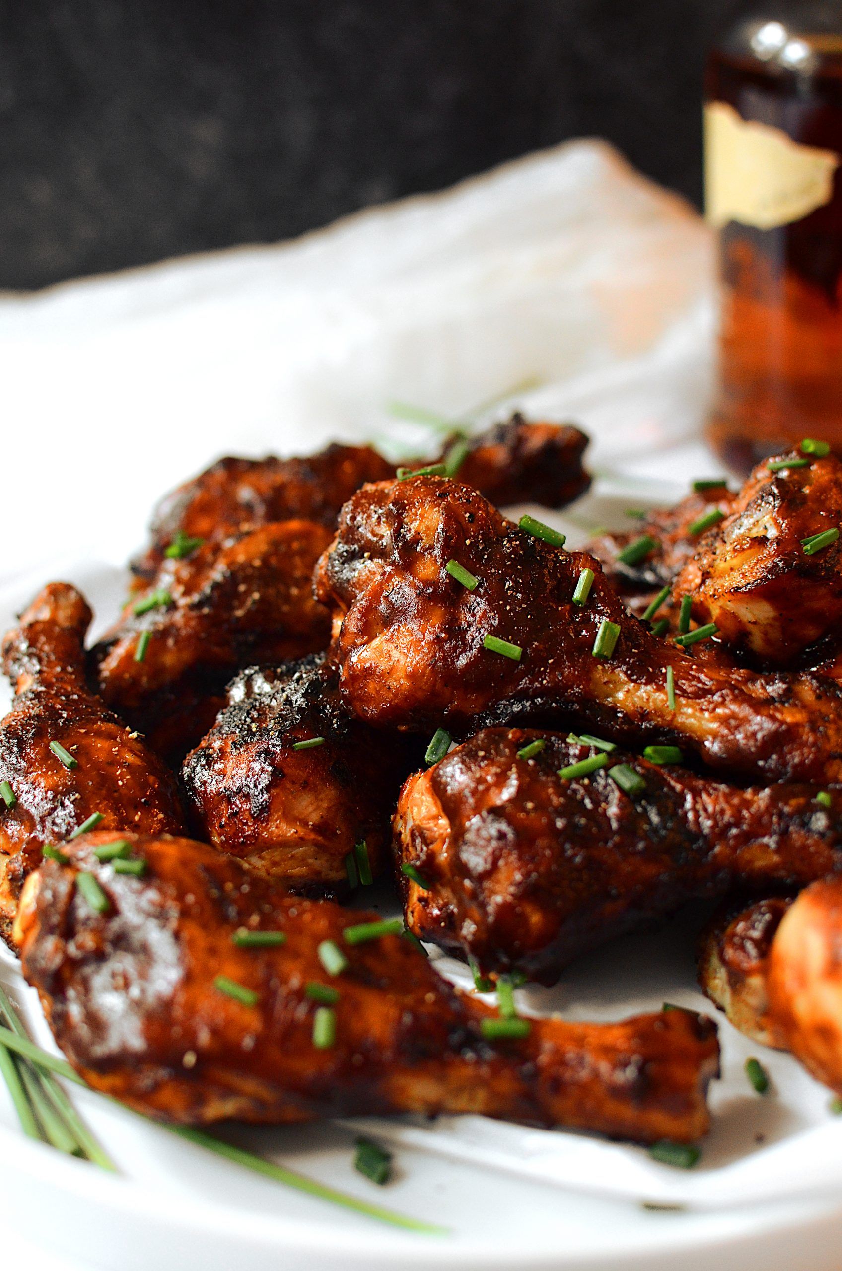 A white plate topped with chicken wings and chives