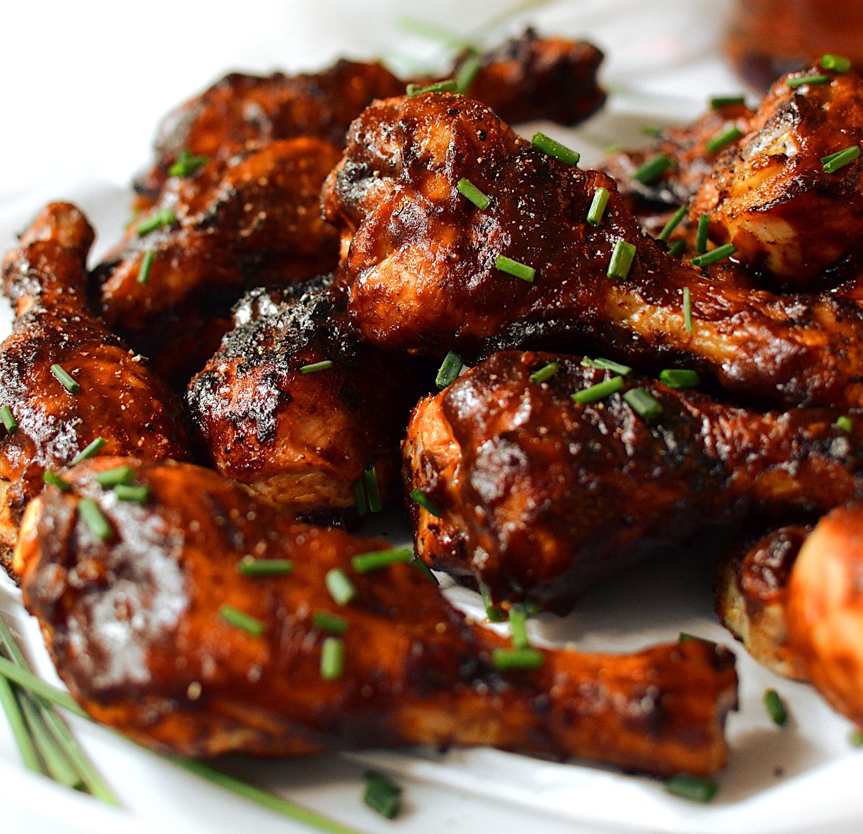 A white plate topped with chicken wings and green onions
