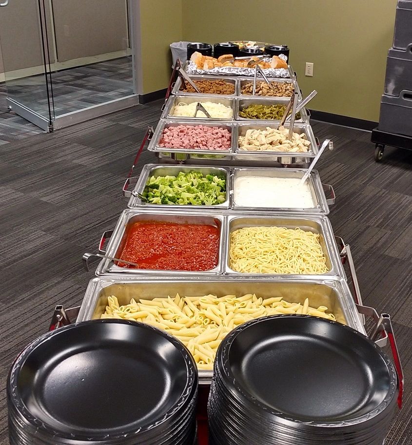 A buffet table with a variety of food and plates.