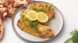 A white plate topped with fried fish and lemon slices.