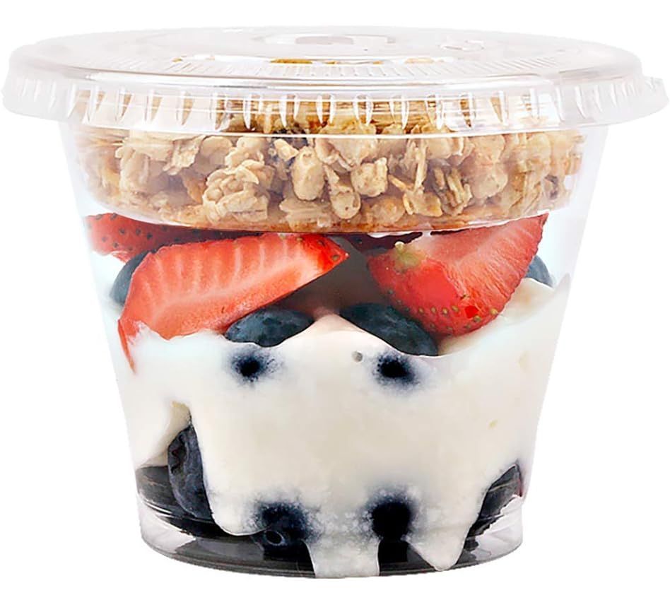 A cup of yogurt with strawberries and blueberries and granola on top.