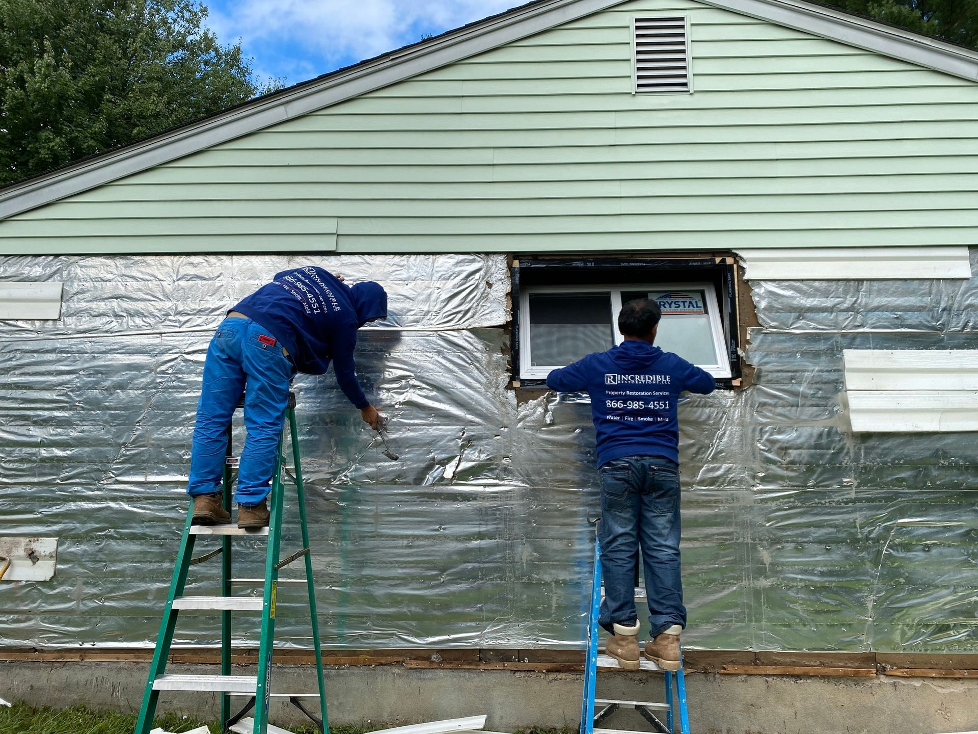 Two men are working on the side of a house.