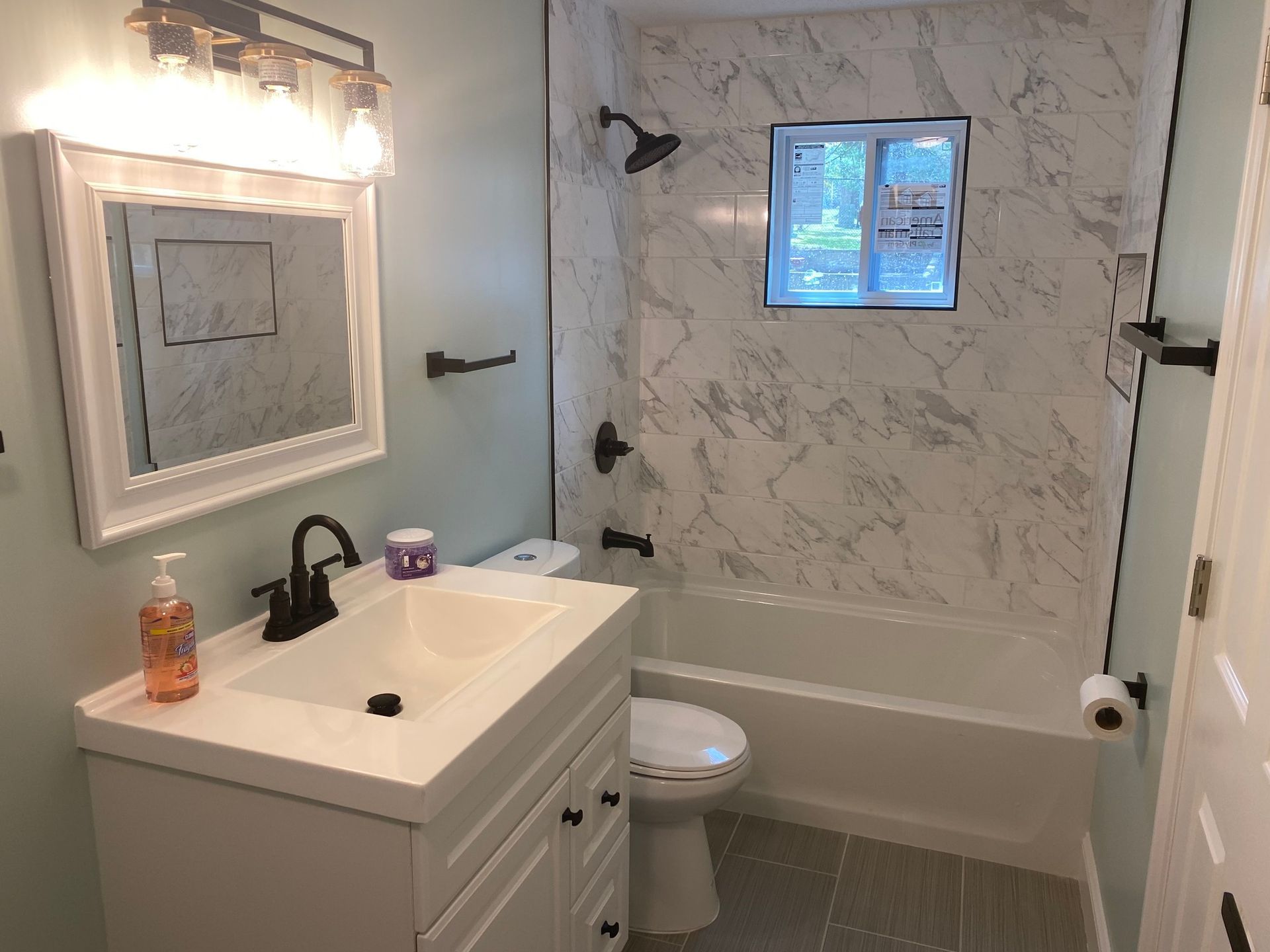 A bathroom with a sink , toilet , tub and mirror.