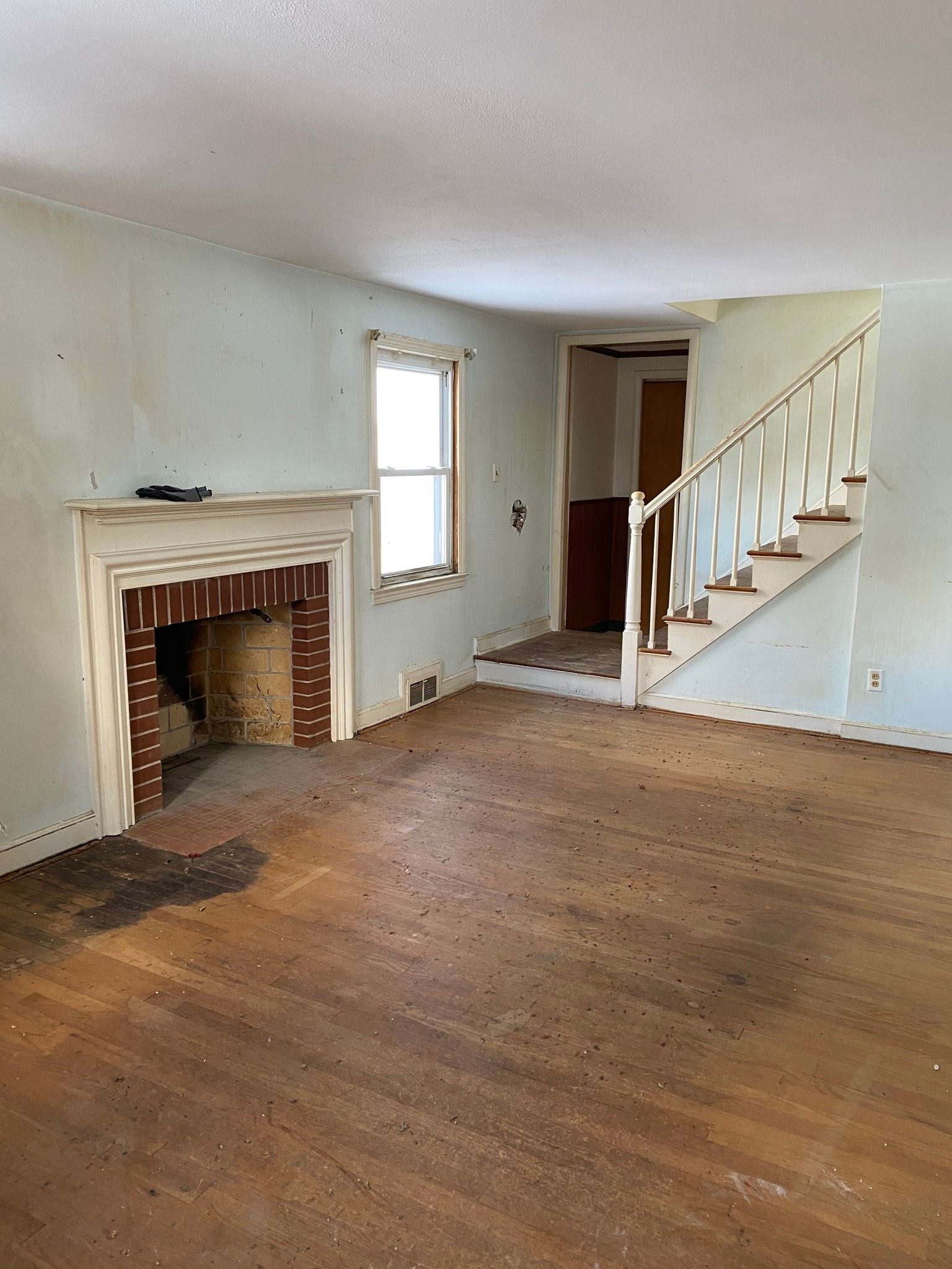 An empty living room with a fireplace and stairs.
