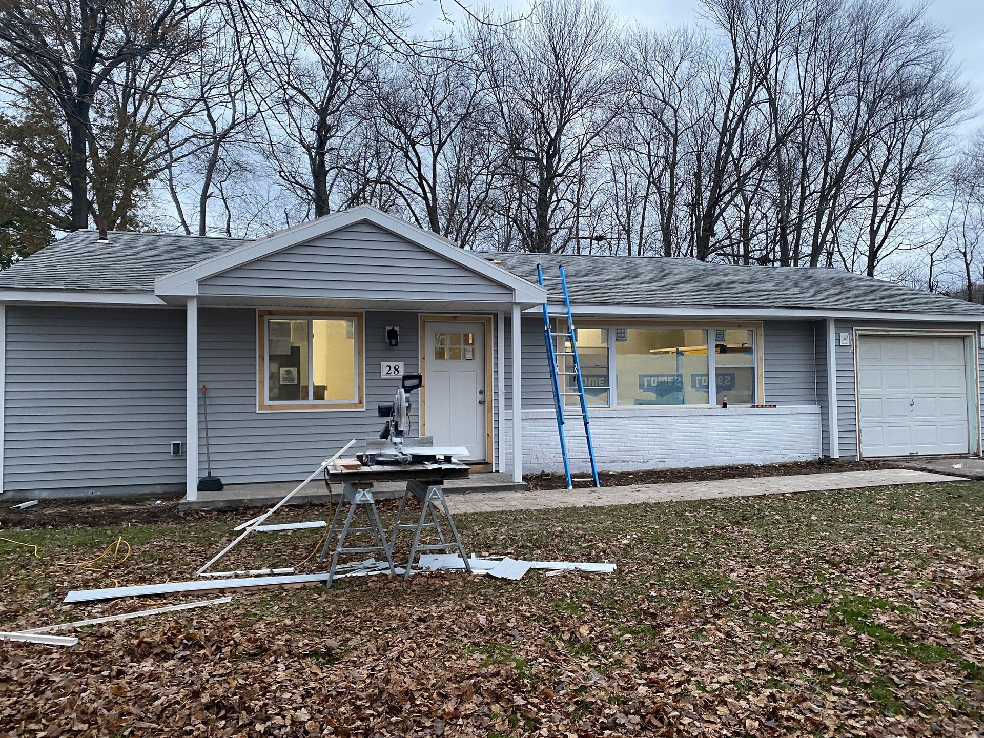 A house is being remodeled with a table saw in front of it.
