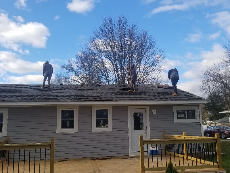 Two men are working on the roof of a house.