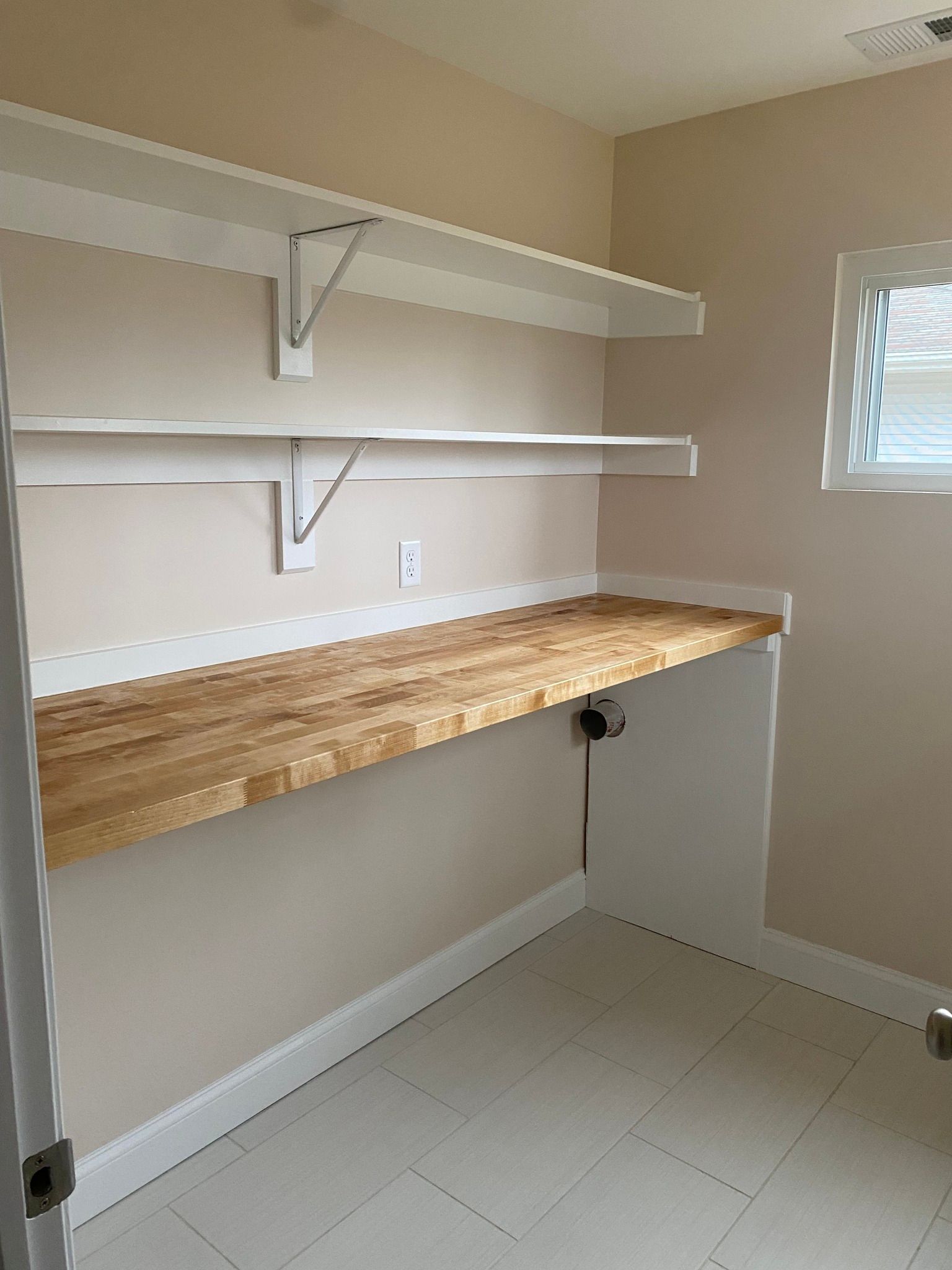An empty room with a wooden desk and shelves.