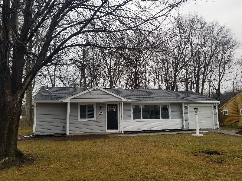 A house with a tree in front of it on a cloudy day.