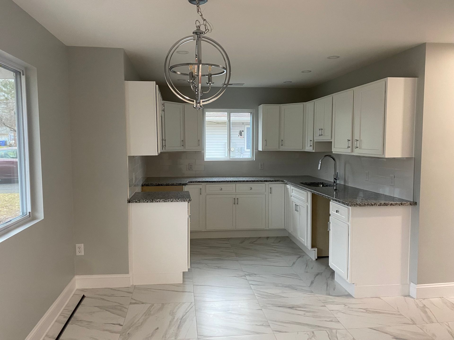 An empty kitchen with white cabinets and granite counter tops