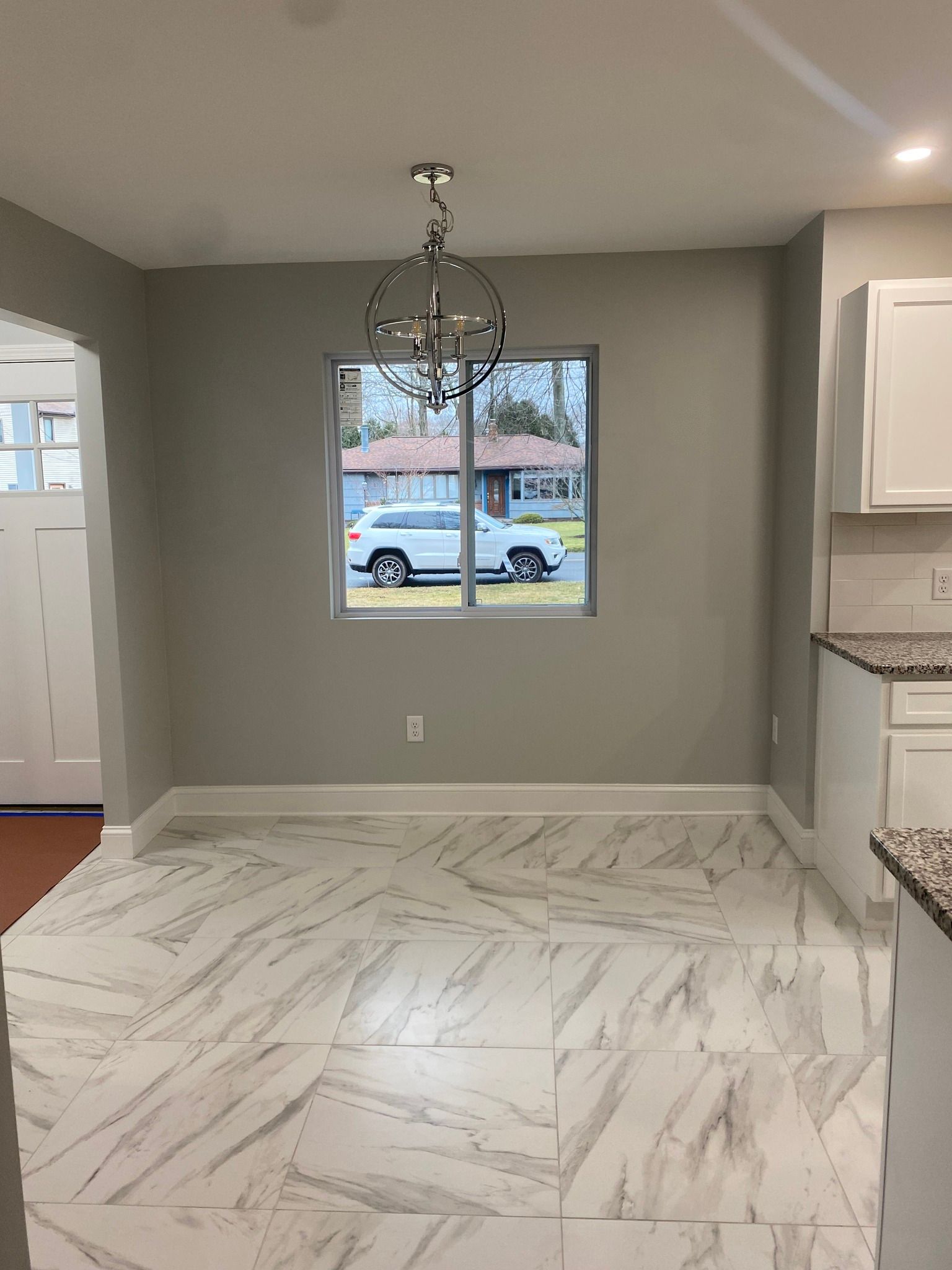 An empty dining room with a car parked in front of a window.