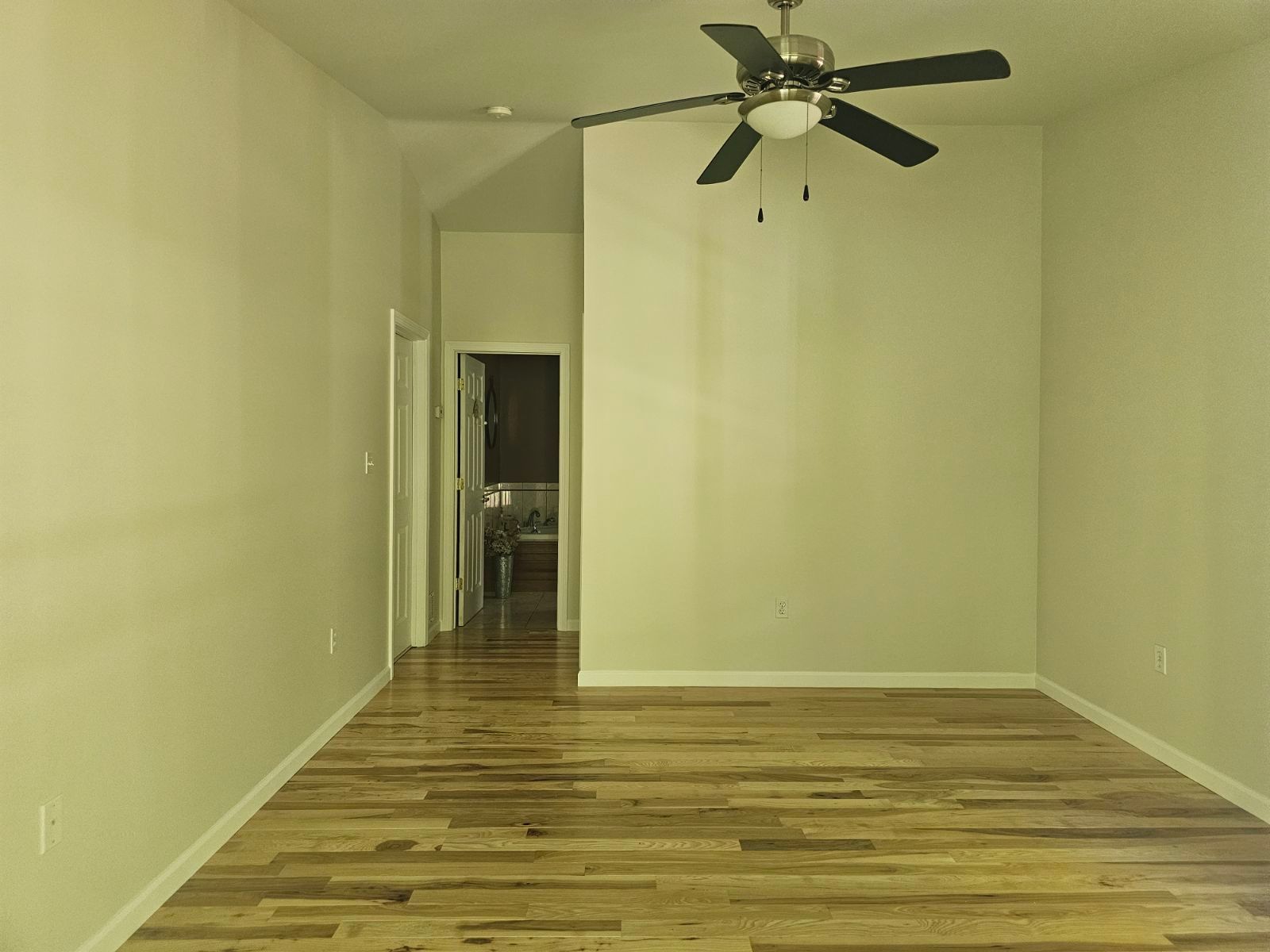 An empty room with hardwood floors and a ceiling fan