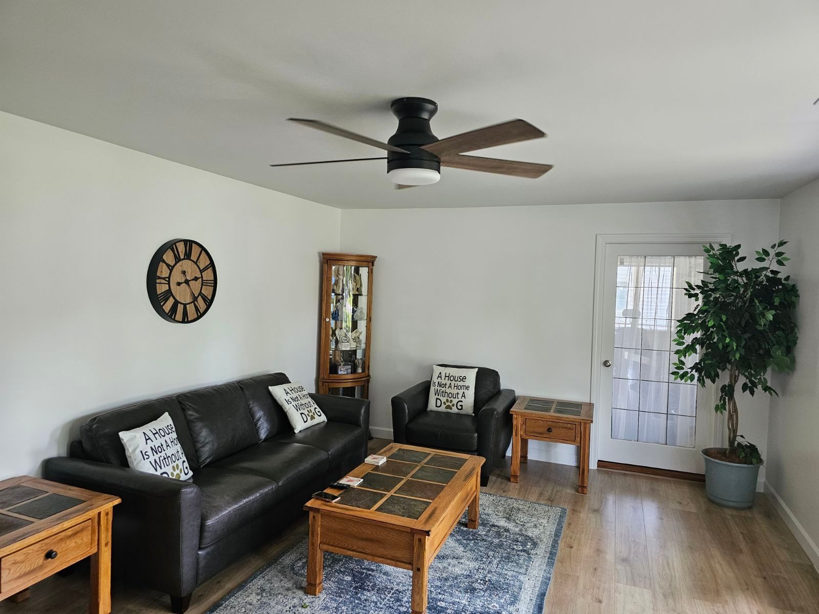 A living room with a couch , chair , coffee table and ceiling fan.
