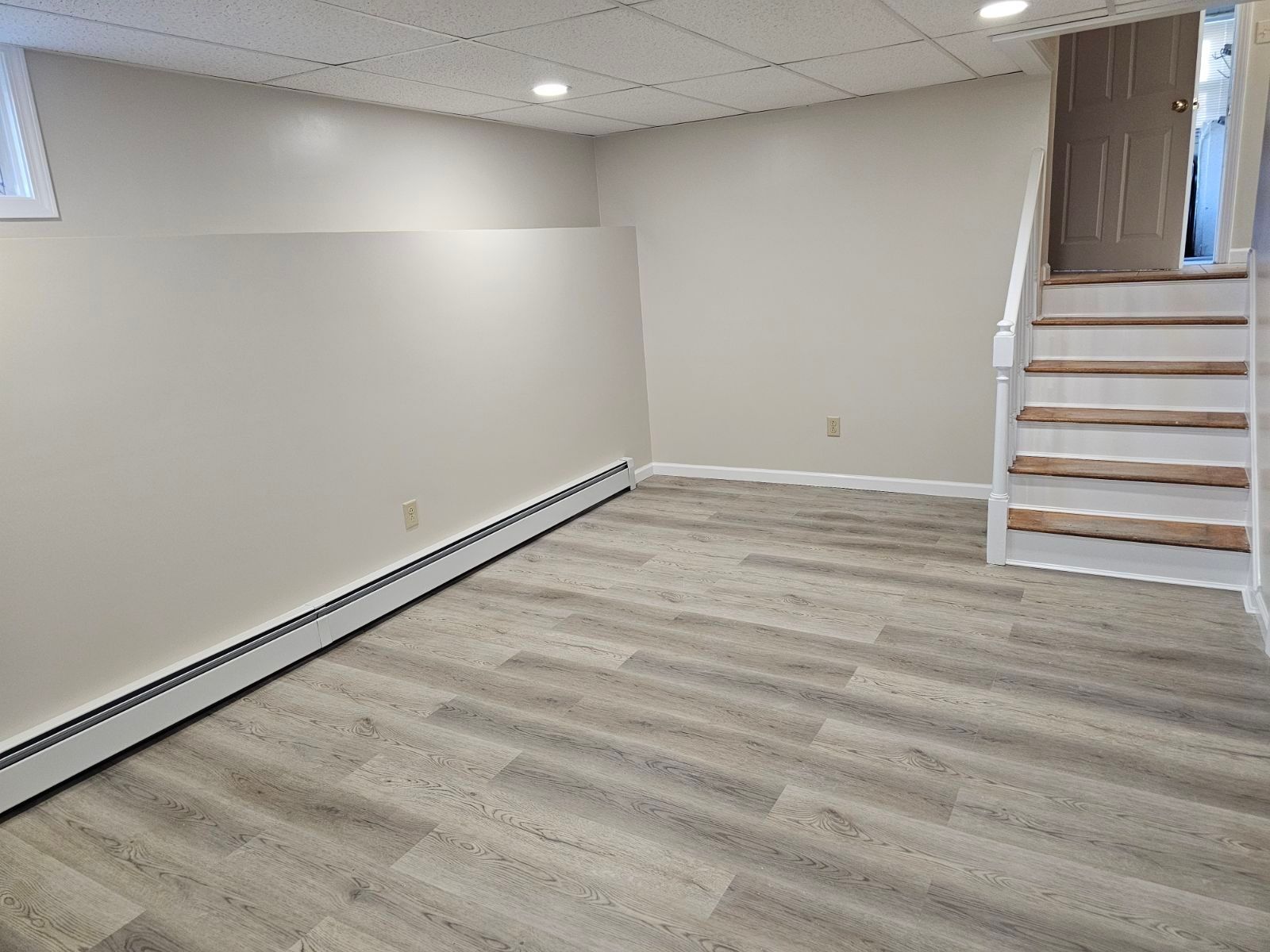 An empty basement with hardwood floors and stairs.