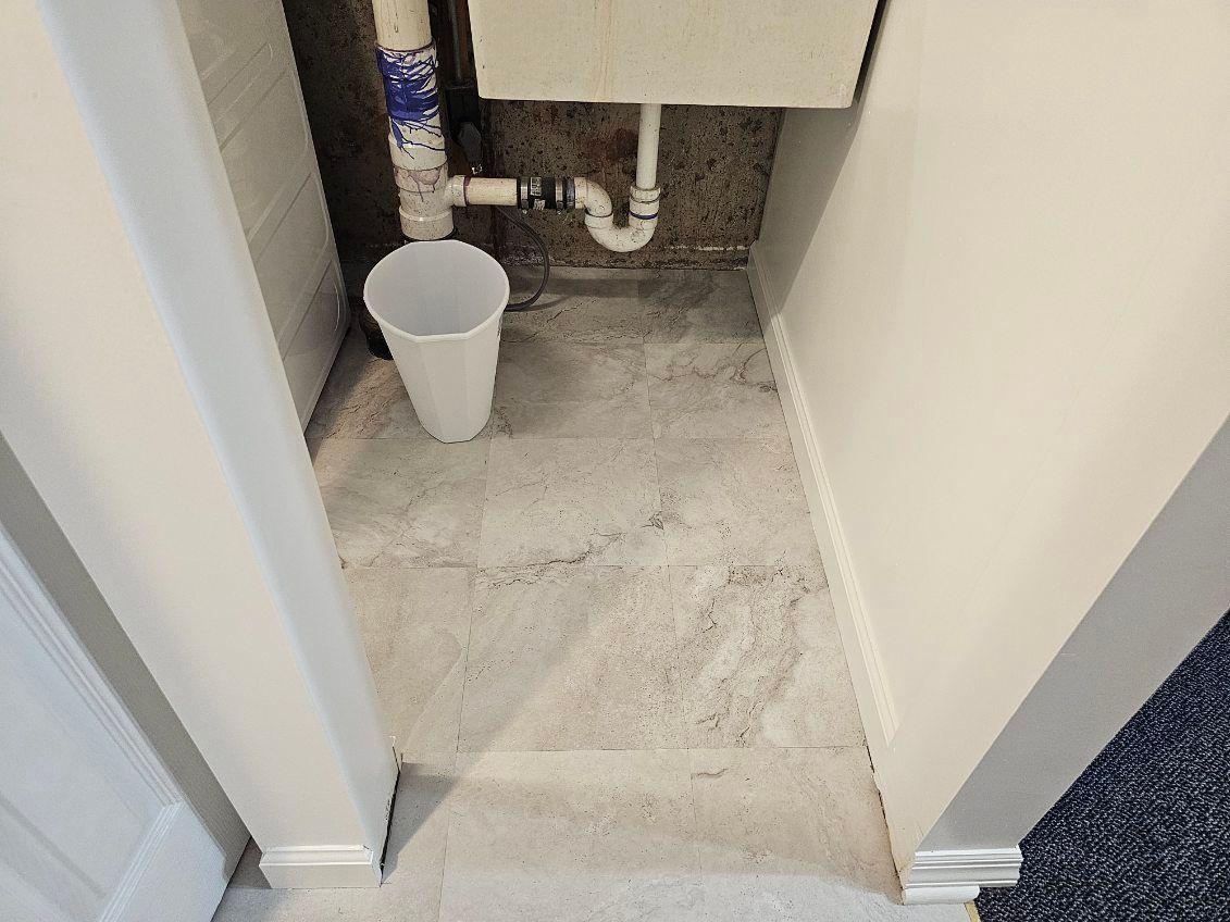 A bathroom with a sink and a trash can on the floor.