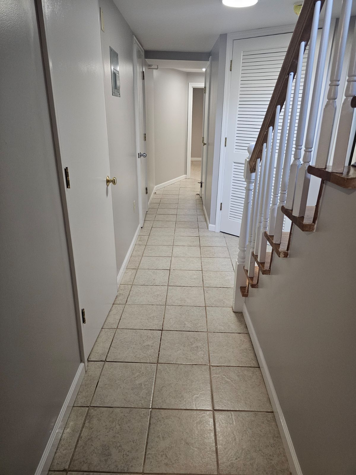 A long hallway with stairs leading up to the second floor of a house.