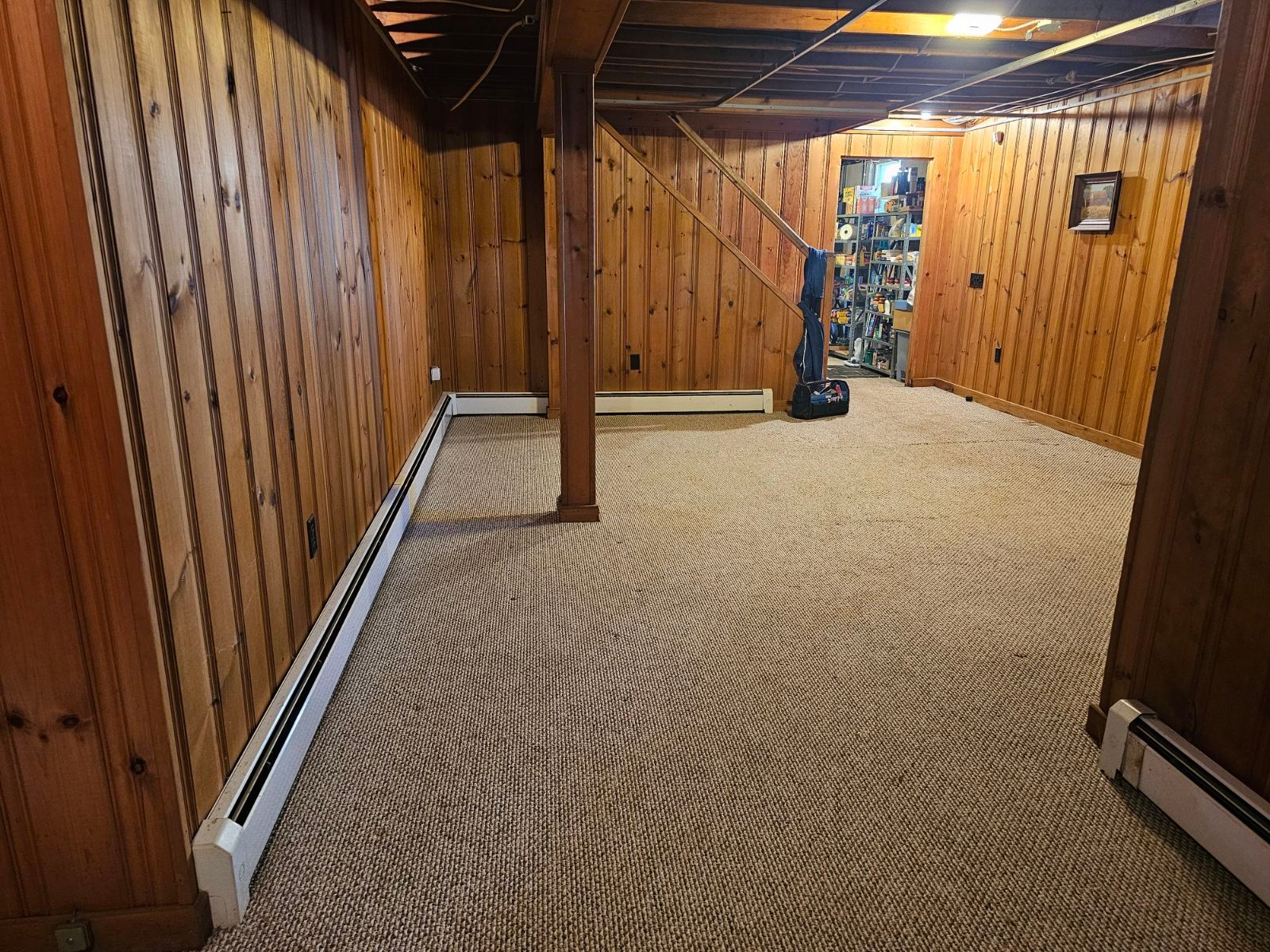 An empty basement with wood paneling and a basketball hoop.