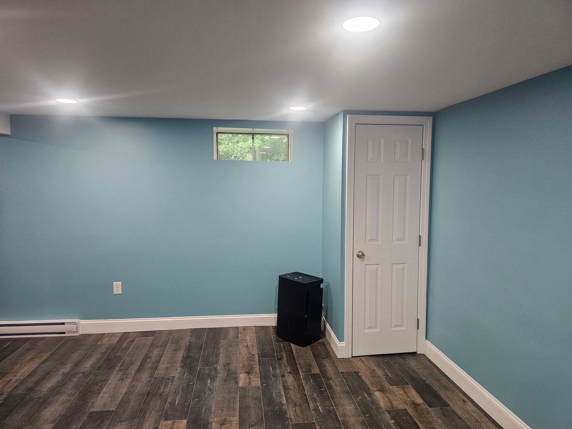 An empty room with blue walls and wooden floors.