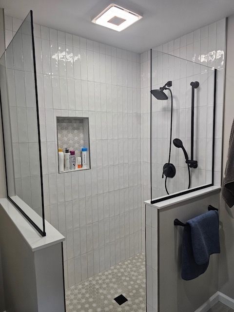 A bathroom with a walk in shower with a glass door