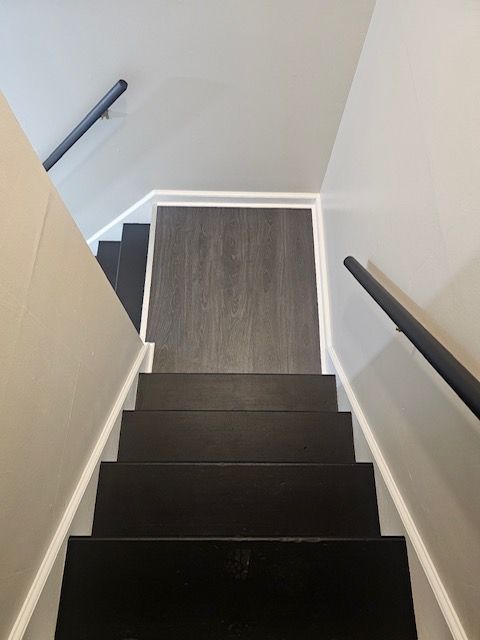 A black staircase with a white railing and a wooden floor